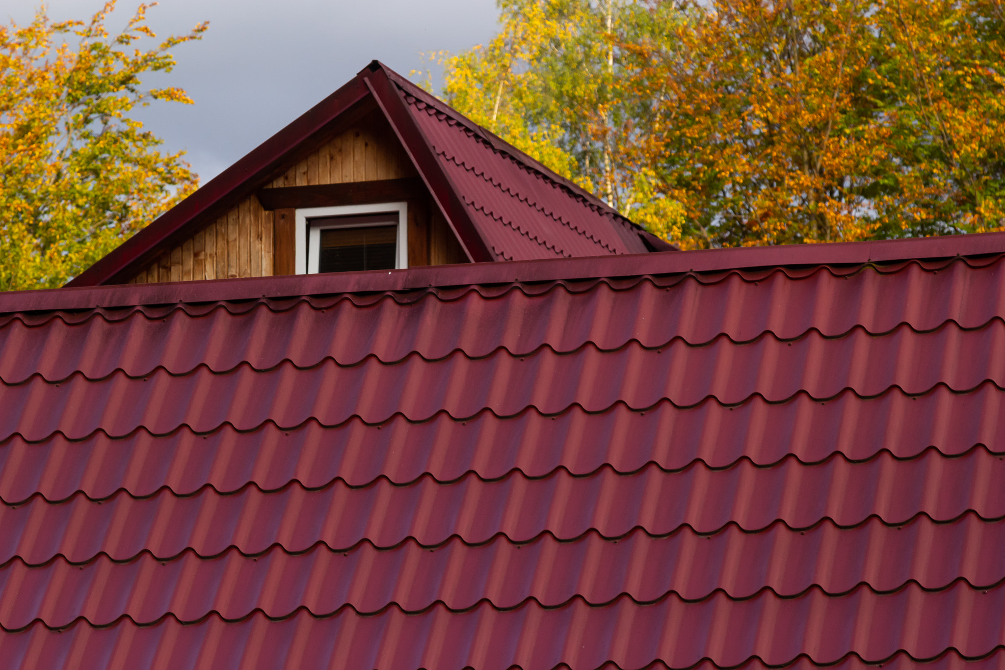 House with new brown metal tile roof and rain gutter. Metallic Guttering System, Guttering and Drain