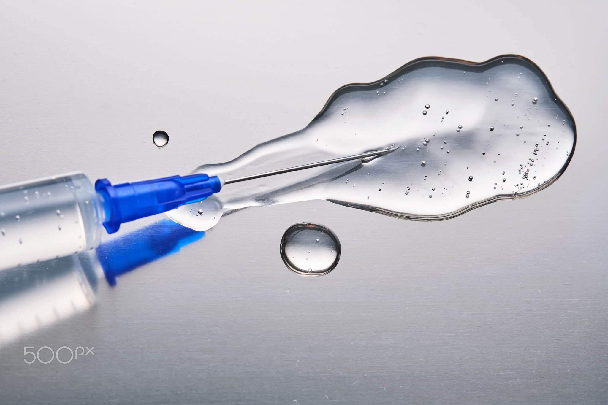 A drop of medicine flowing from a syringe with a needle.