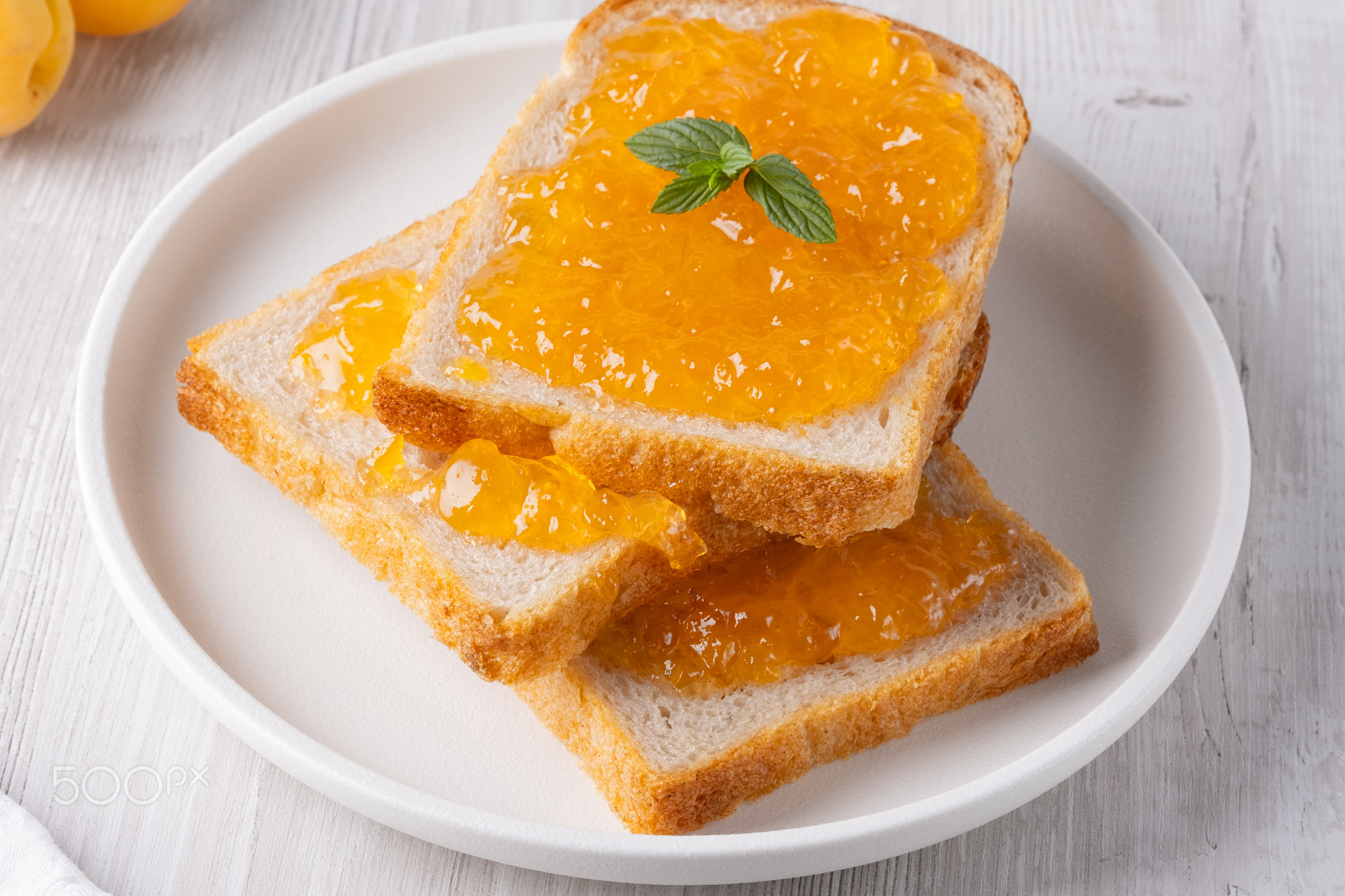 Toasts with tasty apricot jam on a white wooden table