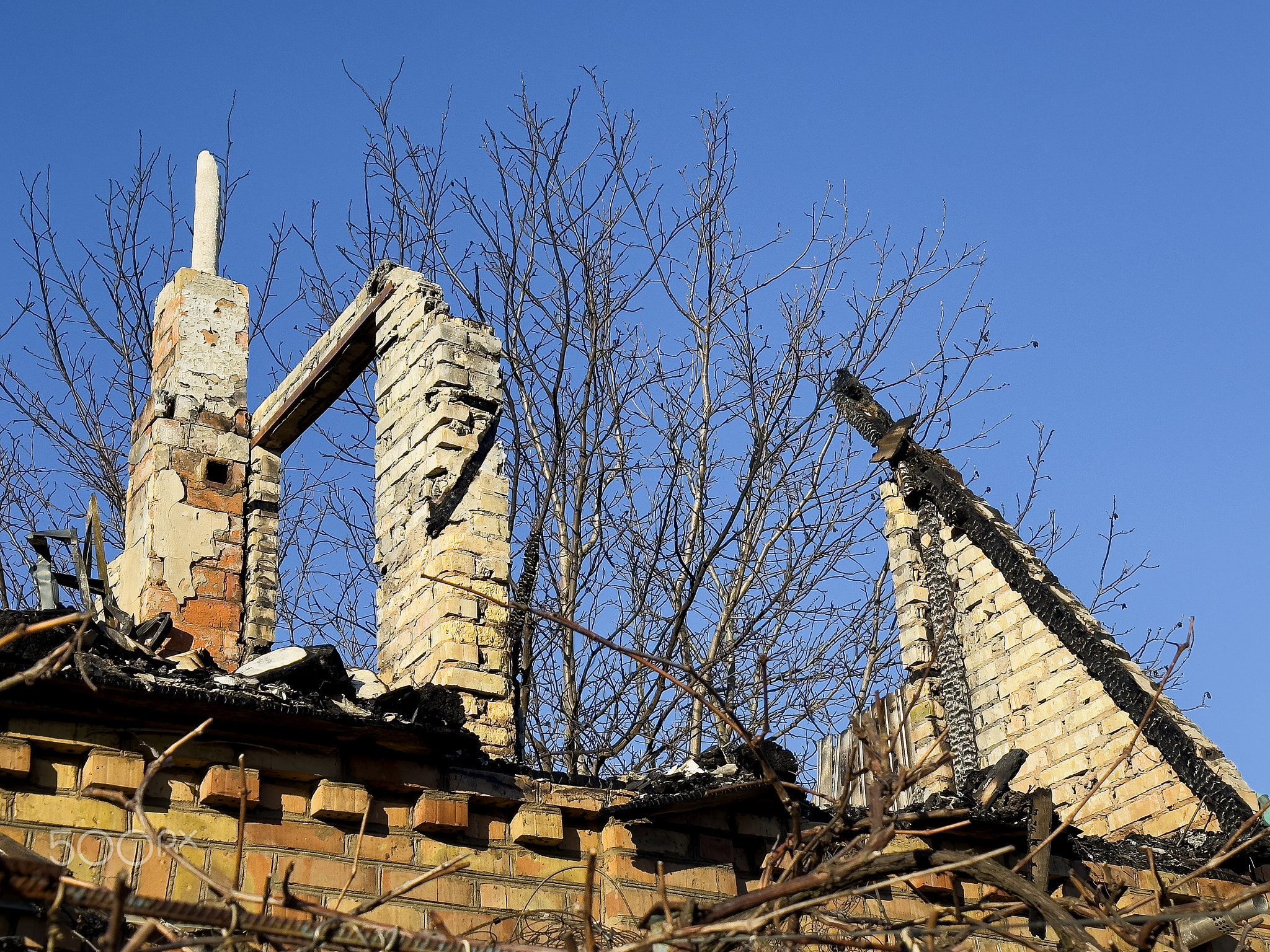 Residential building damaged after fire, showing damage to roof and chimney