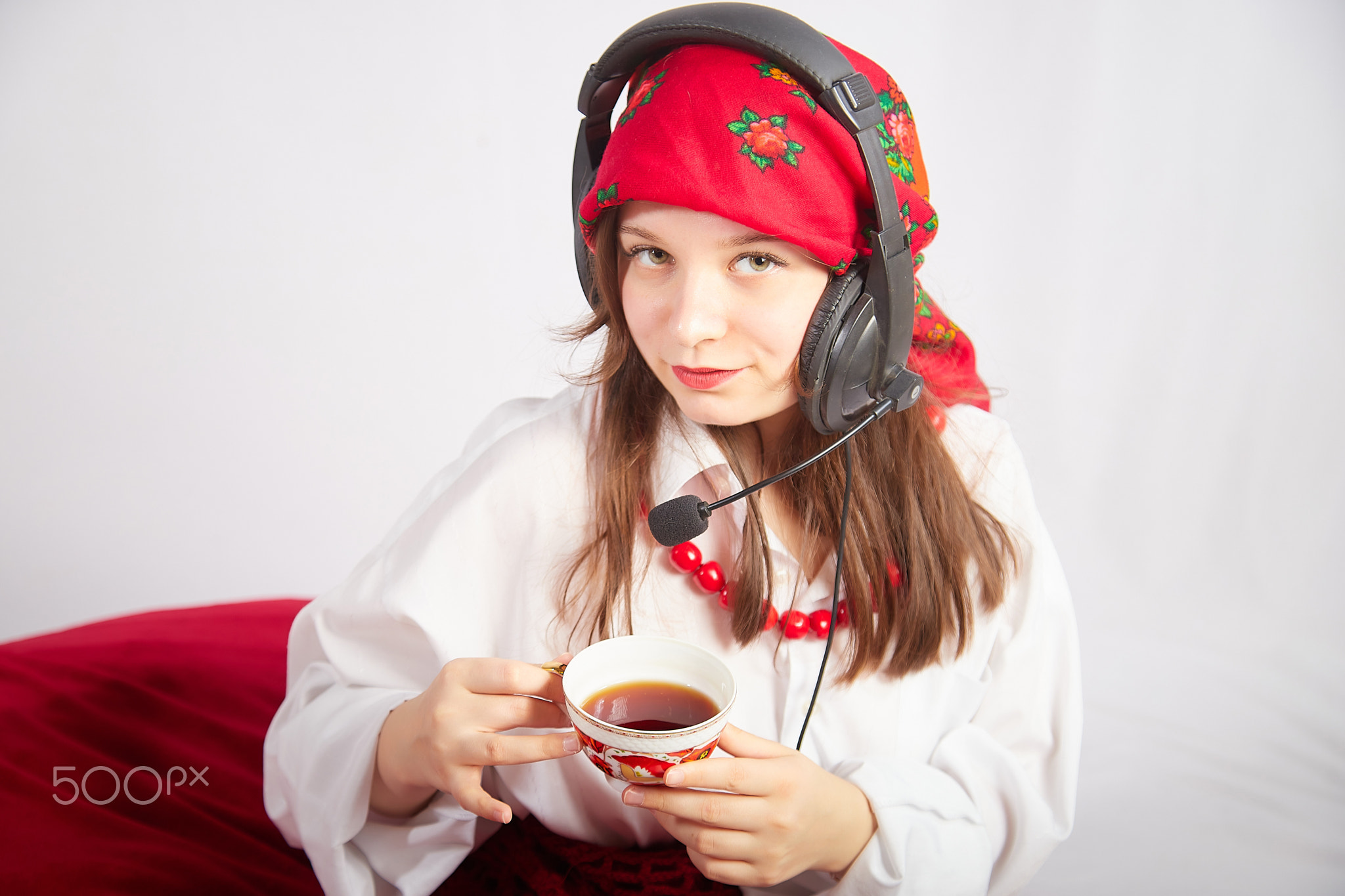 Portrait of young girl in a bright red scarf and large headphones with