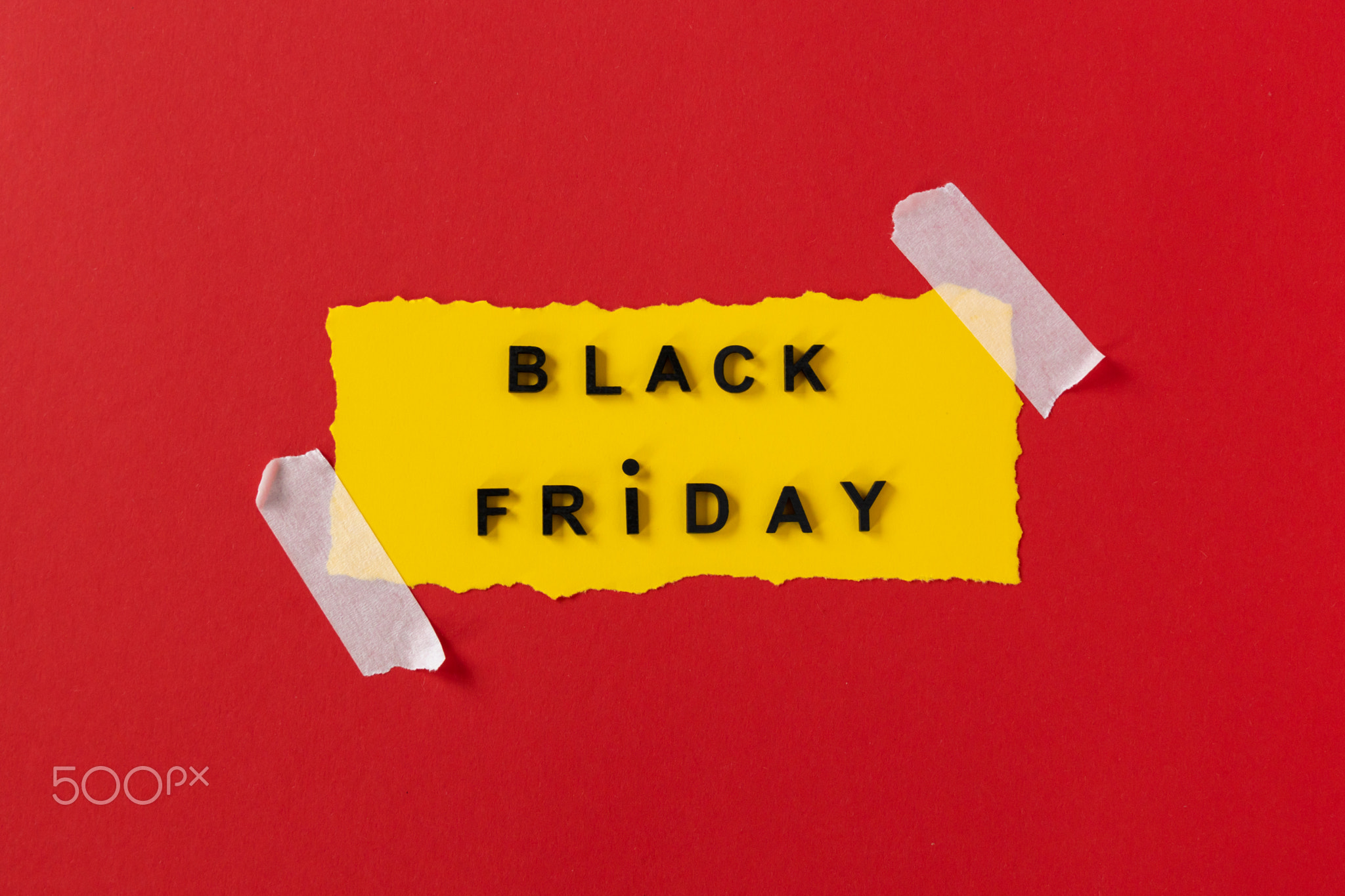 Black friday concept. Top view of yellow torn paper sheet and black