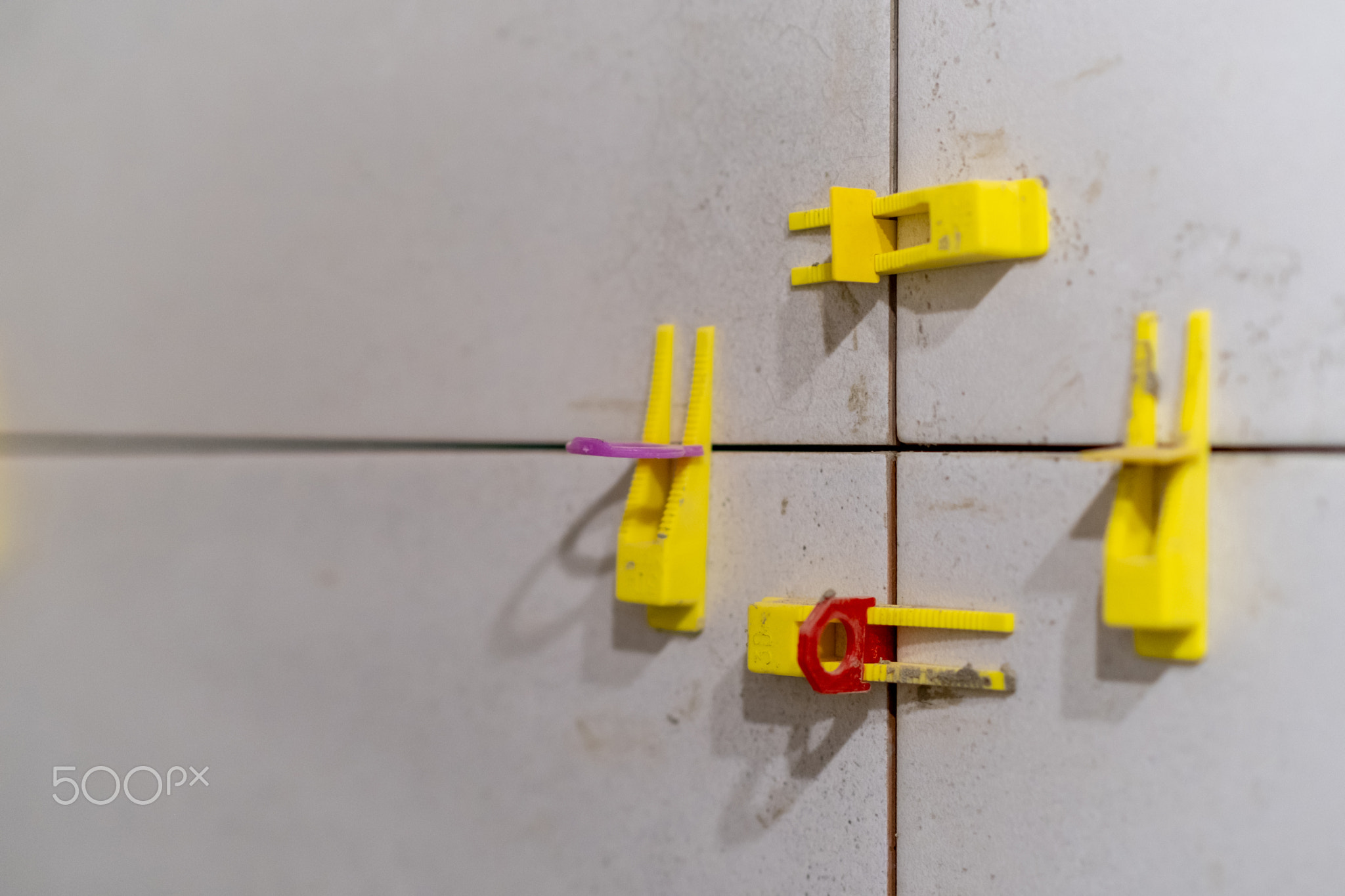 Detailed view of tile leveling system in use with plastic clips and wedges.