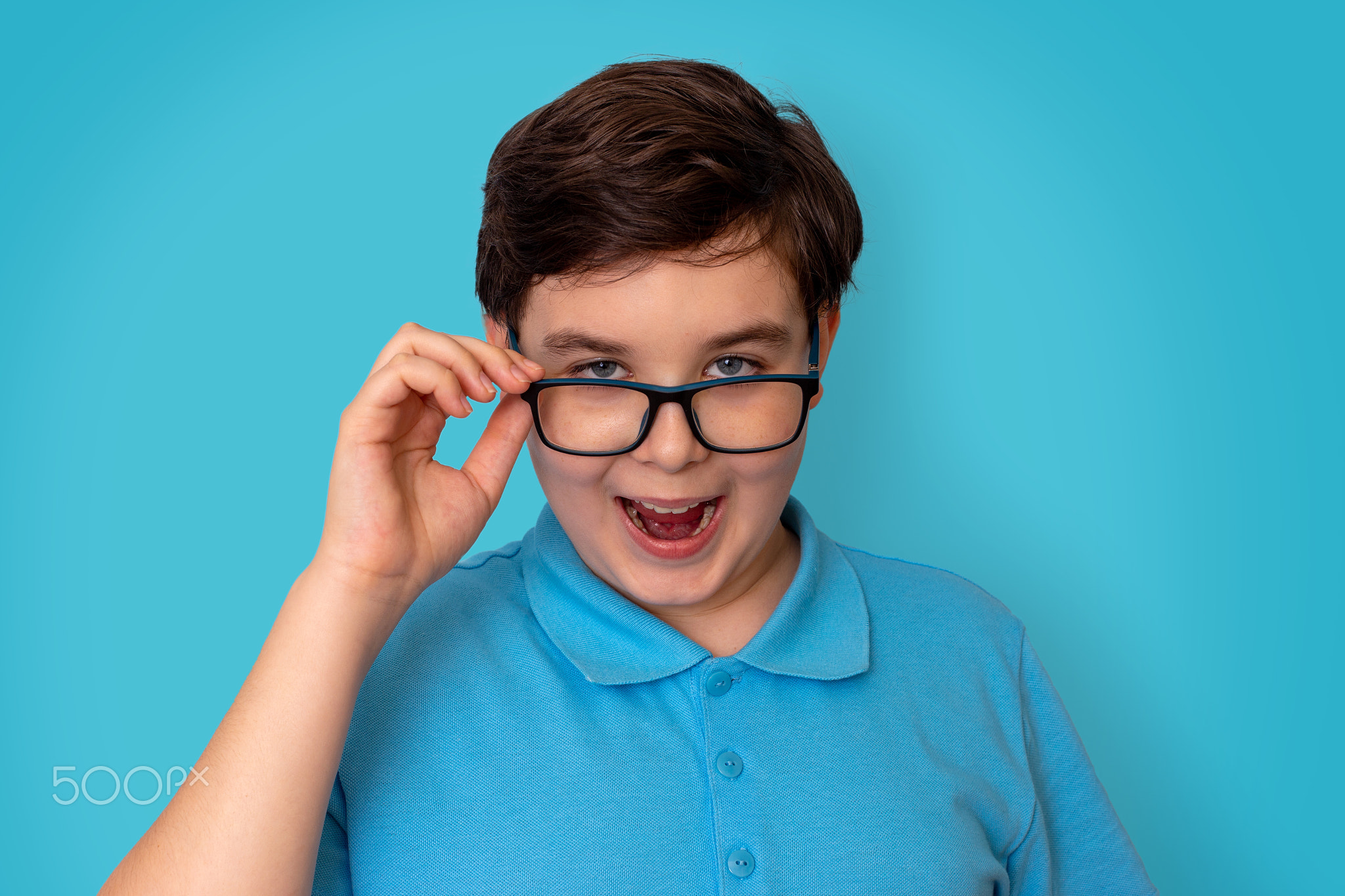 A funny handsome boy, dark-haired, wearing glasses and a blue T-shirt,