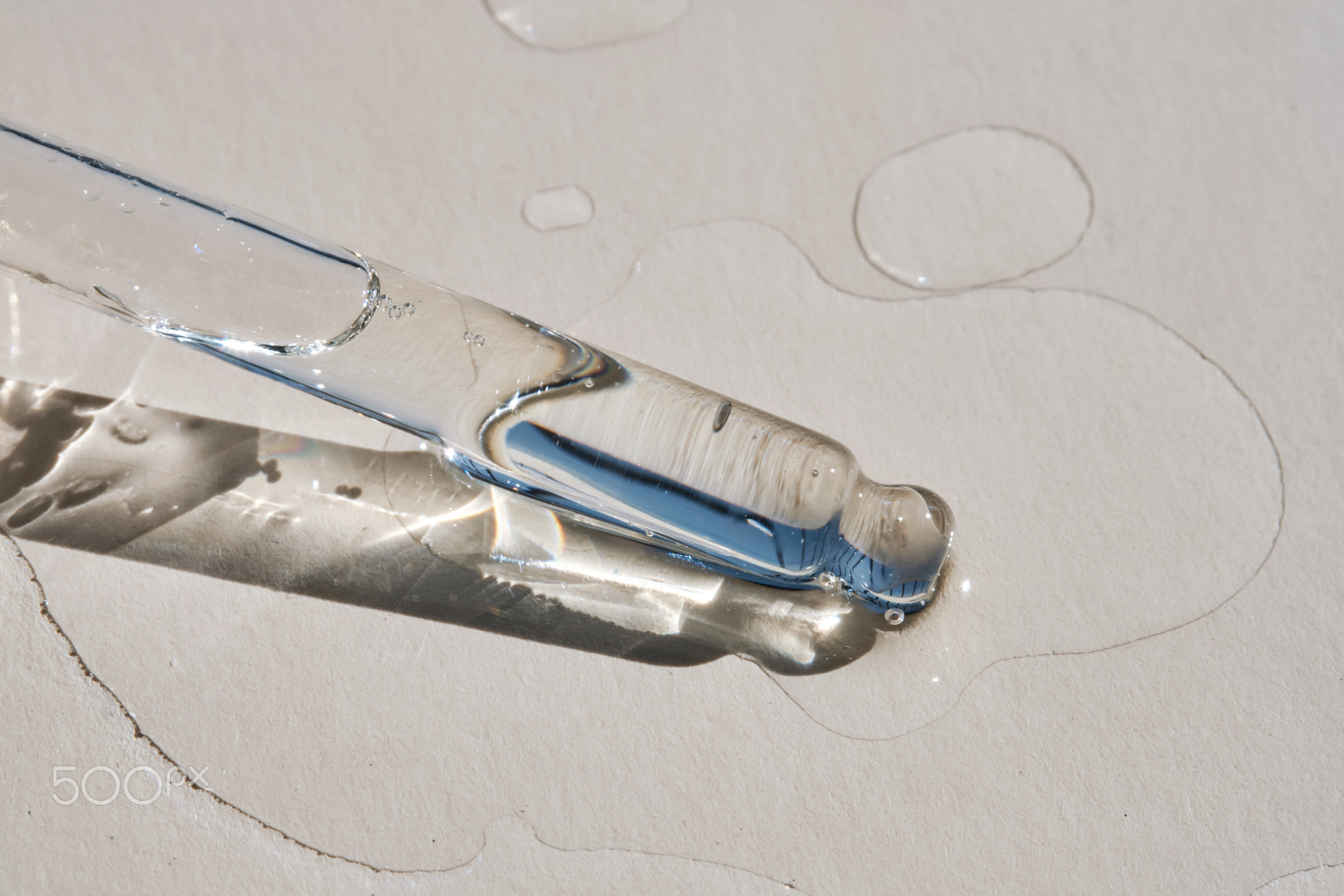 Pipette with serum on a beige background.