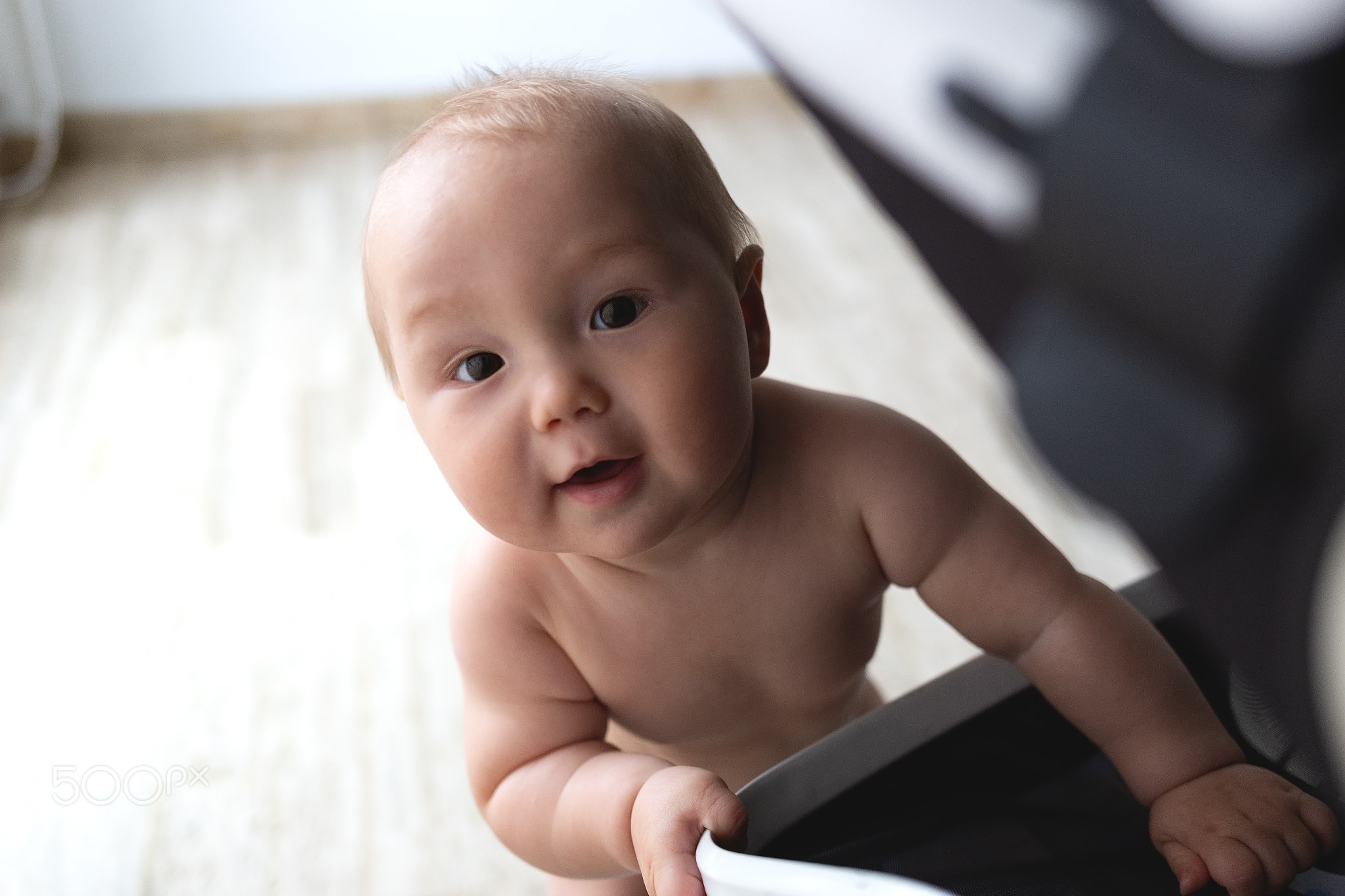 A curious baby reaches out with a joyful expression, exploring the world around them