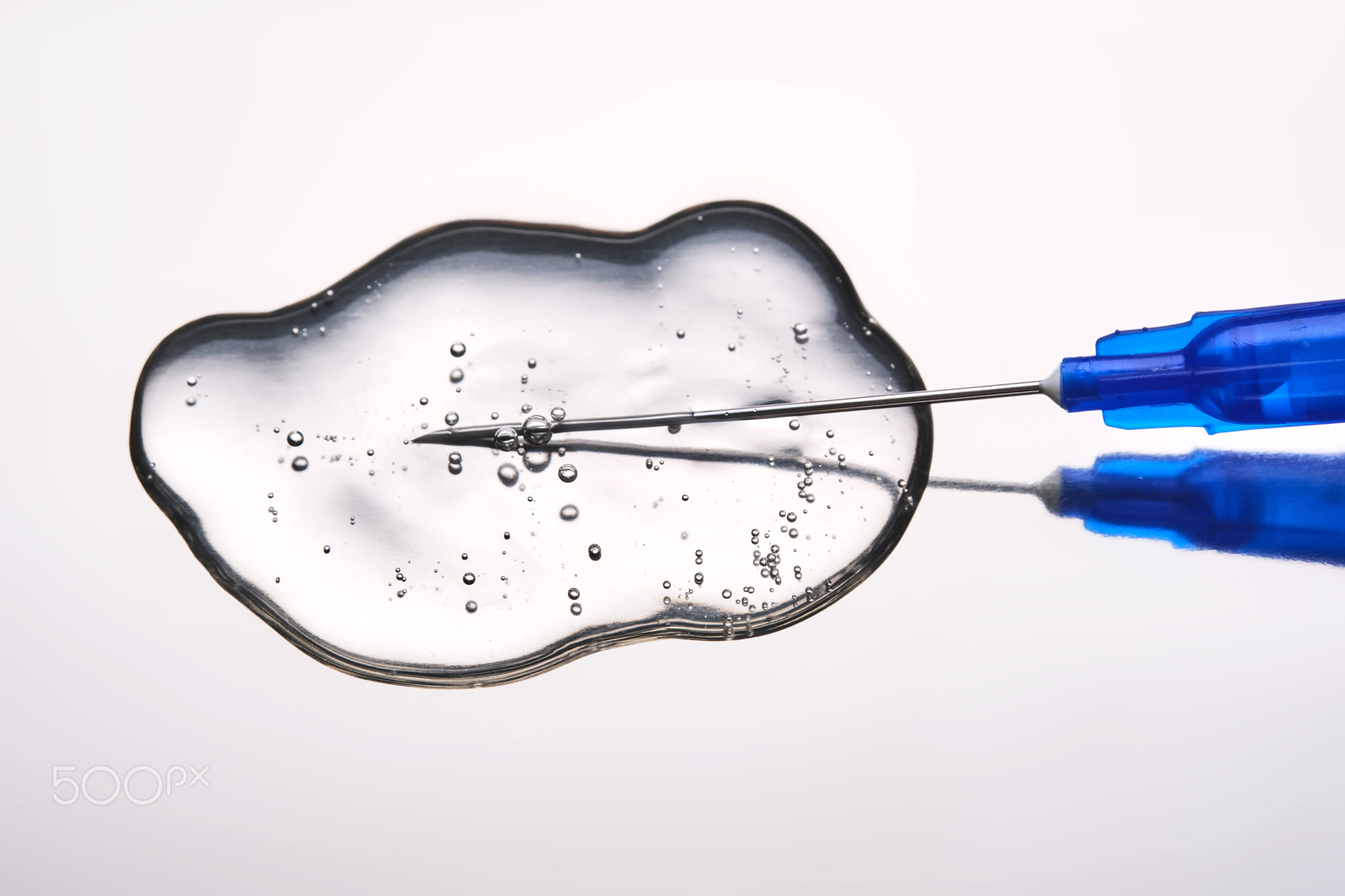 A drop of medicine flowing from a syringe with a needle.