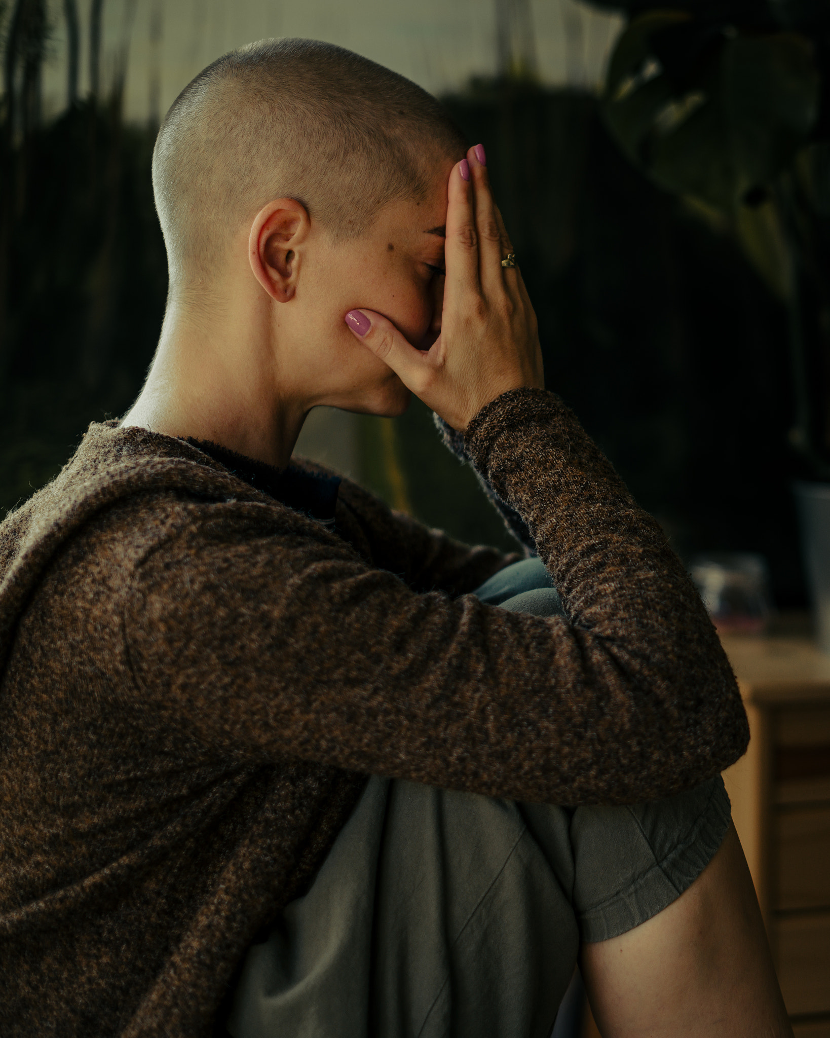 Young female cancer patient with head in hands indoors portrait. Health insurance concept.