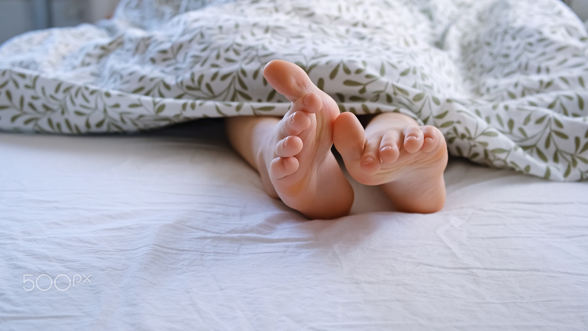 The child shows a thumbs up on his feet. Big toes. Small tender baby