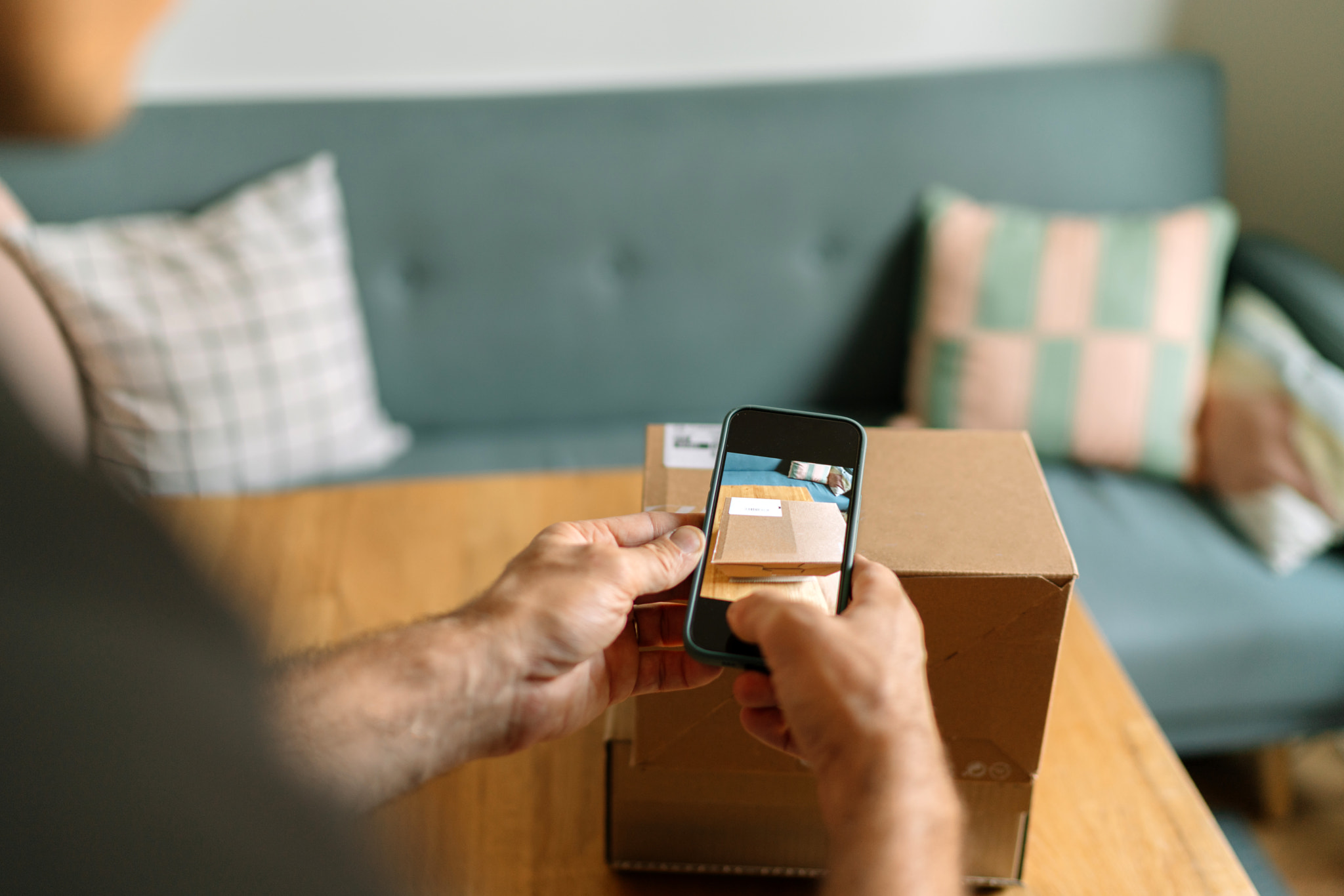 Cropped hands of man photographing parcel at home