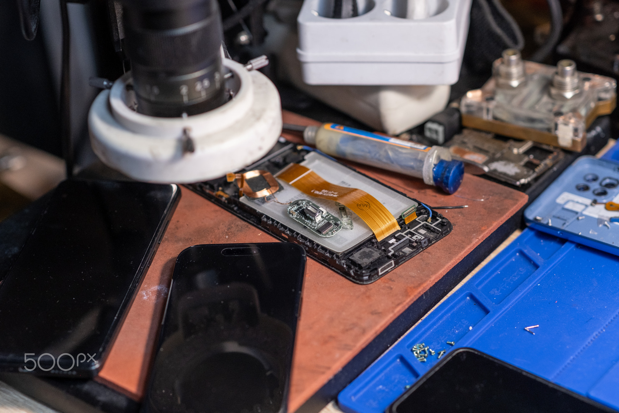 A technician conducts a battery replacement for a mobile phone on a workbench filled with various