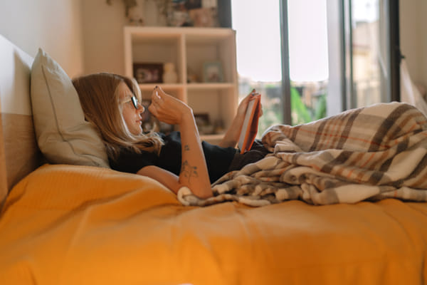 Woman reading digital book while sitting on bed at home by Olha Dobosh on 500px.com