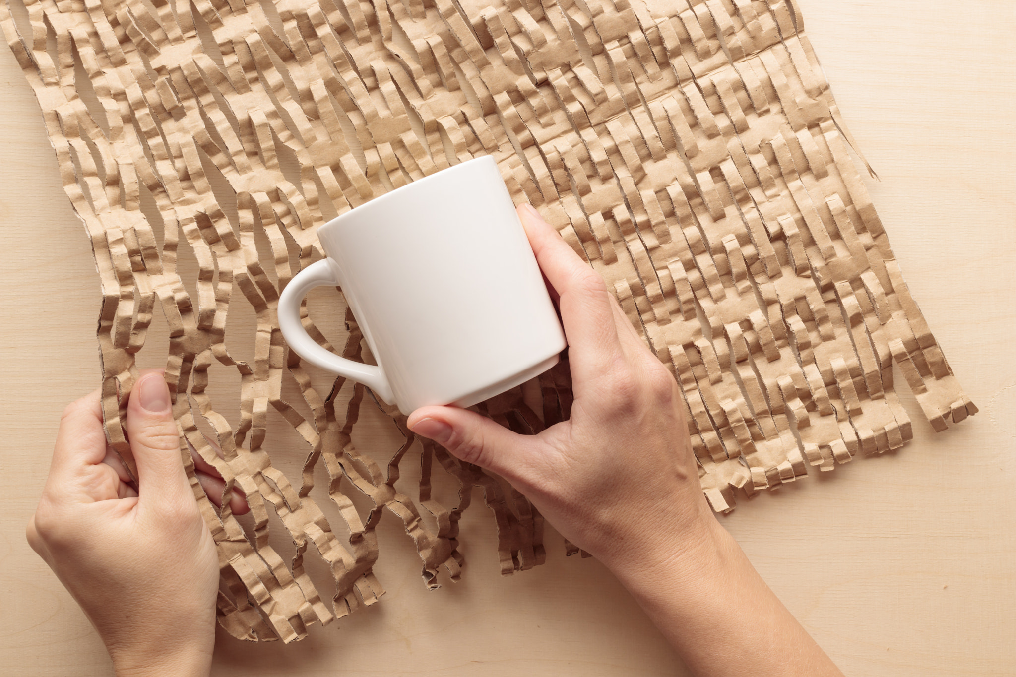 Brown Primary Color Honeycomb Wrapping Paper. Human packs a mug into a brown eco friendly reusable c