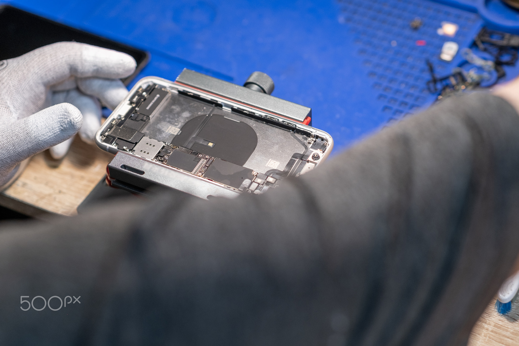 A technician carefully performs phone repair and battery replacement at a service desk, ensuring