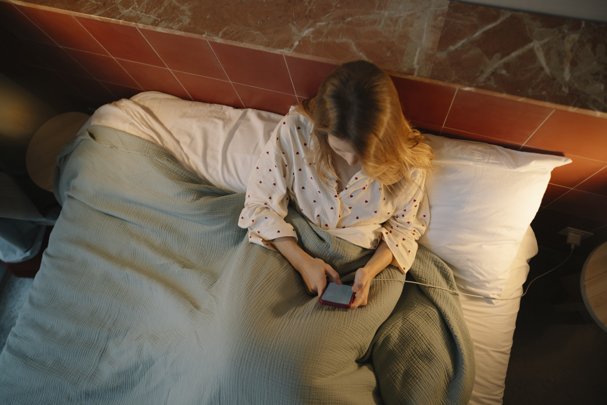High angle view of woman using mobile phone while sitting on bed at home