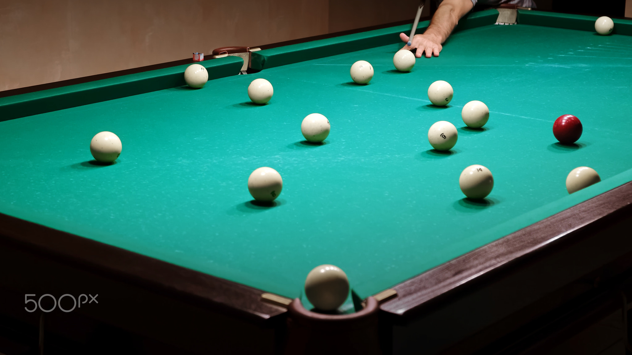 Playing Russian billiards on a green table. Billiard player hits the