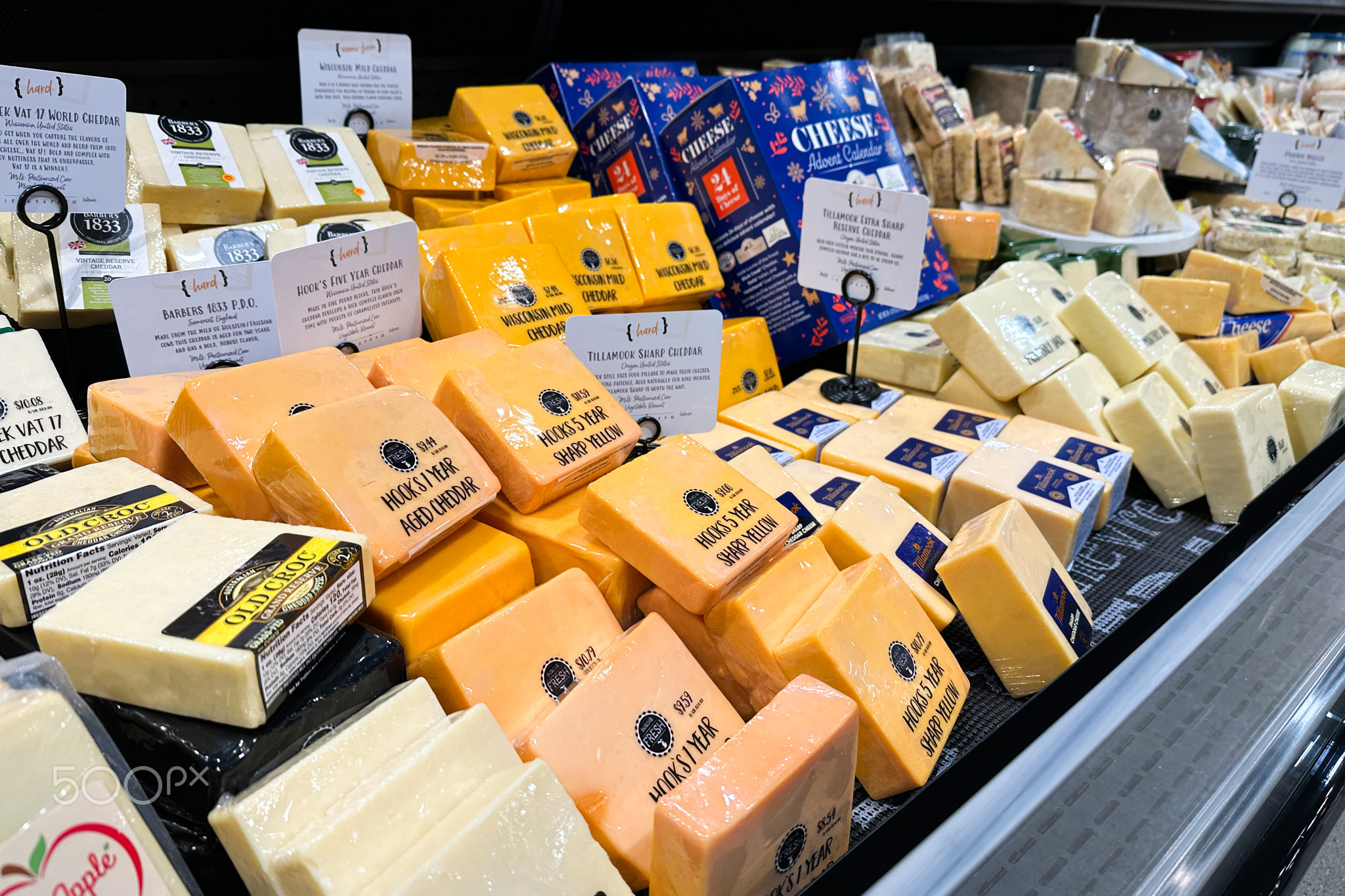 Varieties of cheese bricks on the shelves in a supermarket.