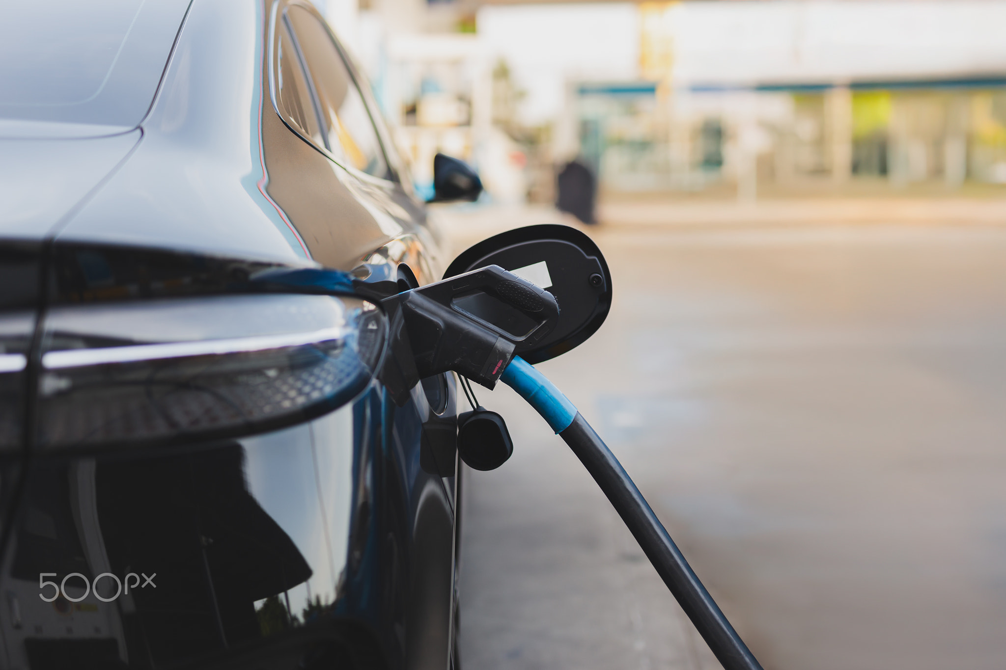 Electric car at charging station with the power cable supply plugged.