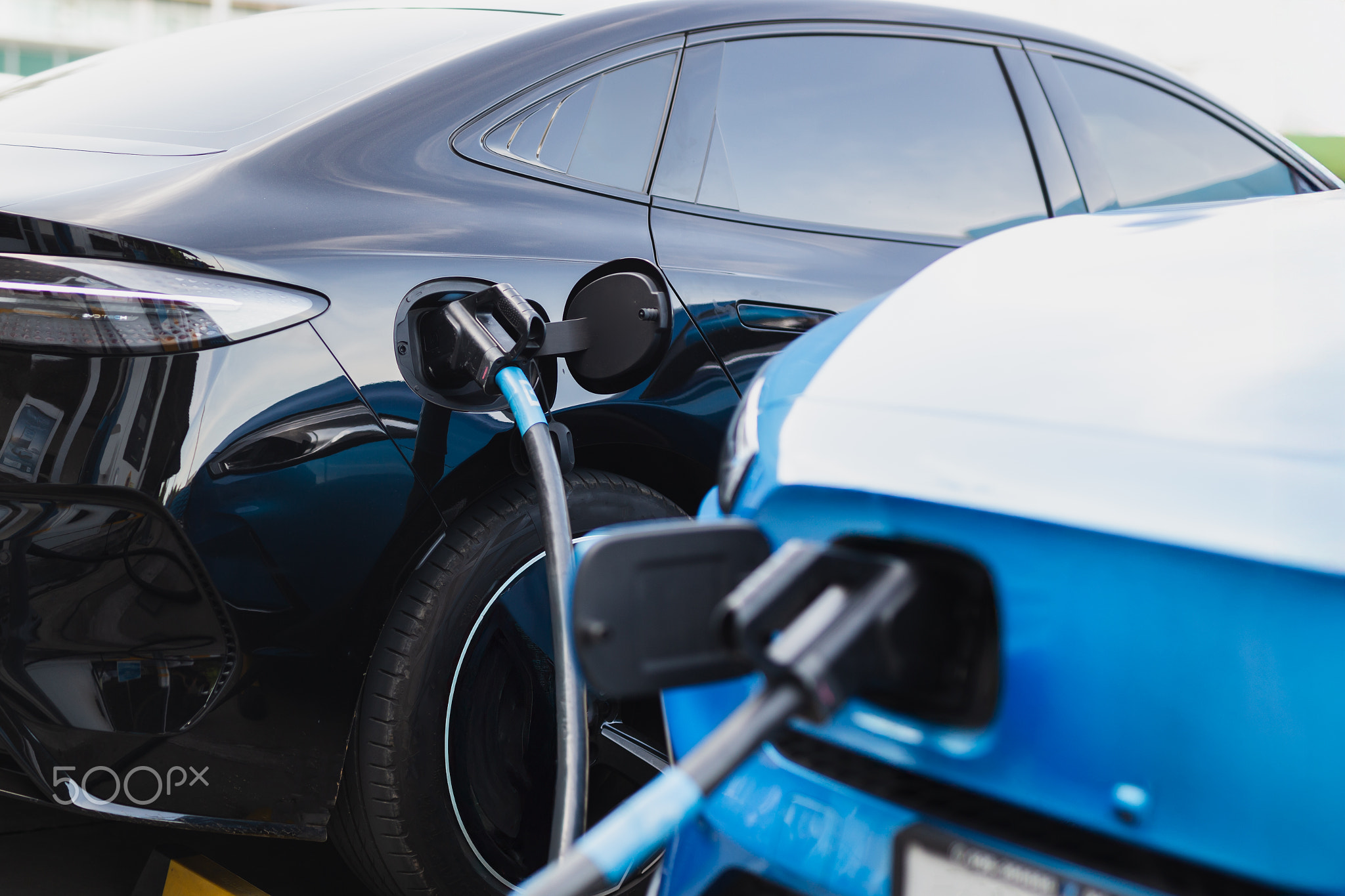 Electric car at charging station with the power cable supply plugged.
