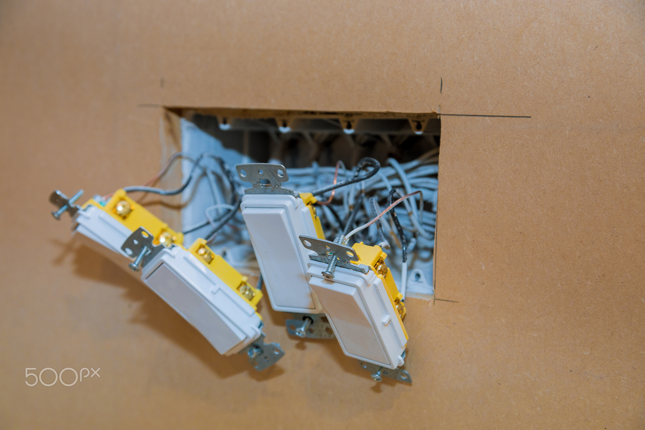 Three electrical switches partially installed in a wall with exposed