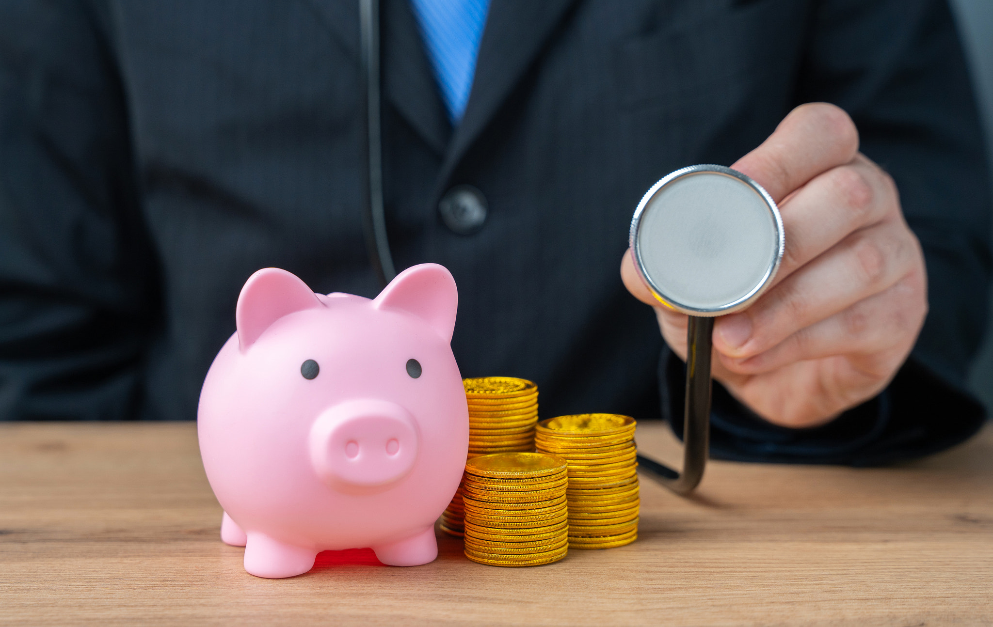 Businessman with stethoscope and piggy bank with coins. Financial health and well-being concept. Man