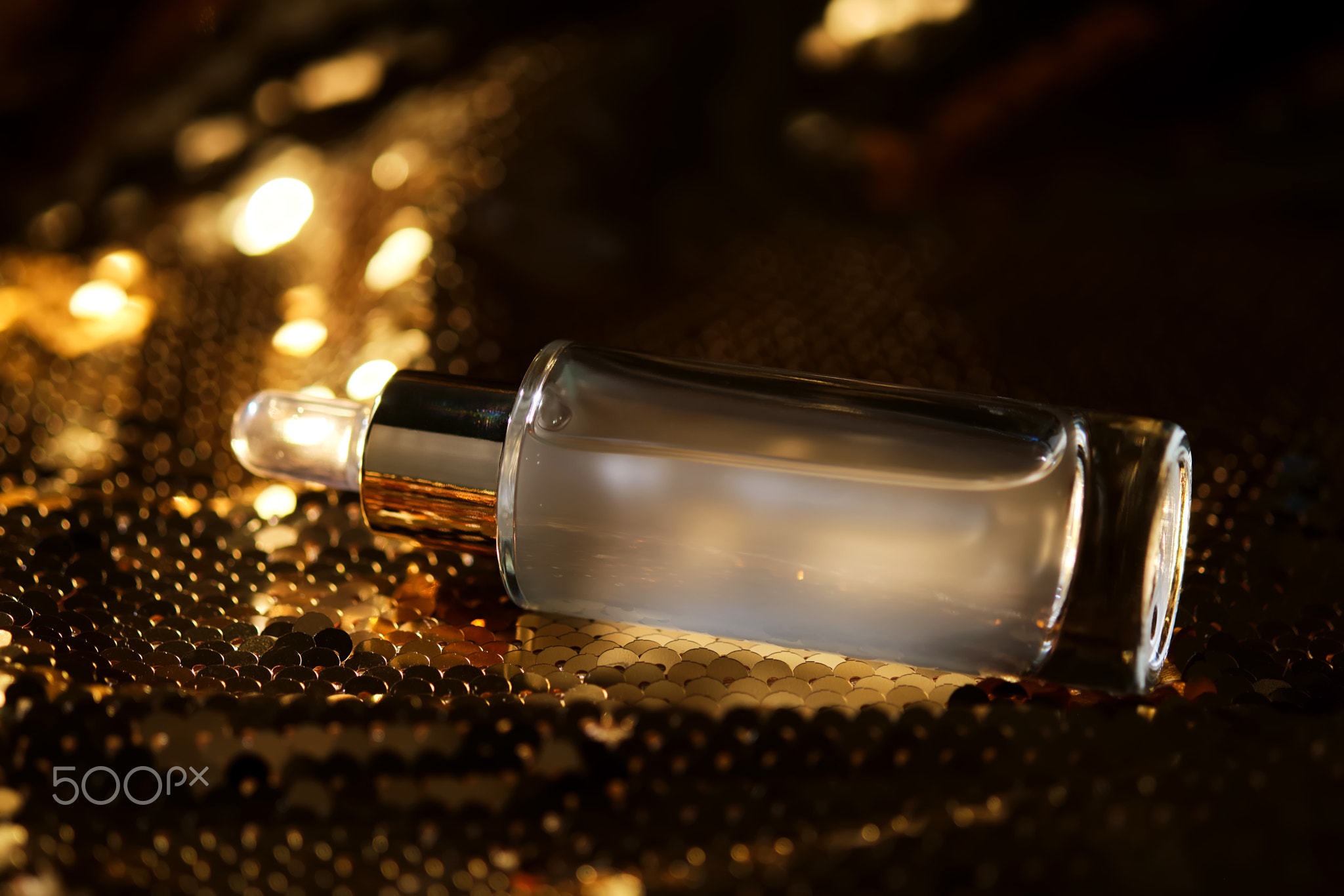 A bottle of cosmetic serum with a pipette on a festive golden background.