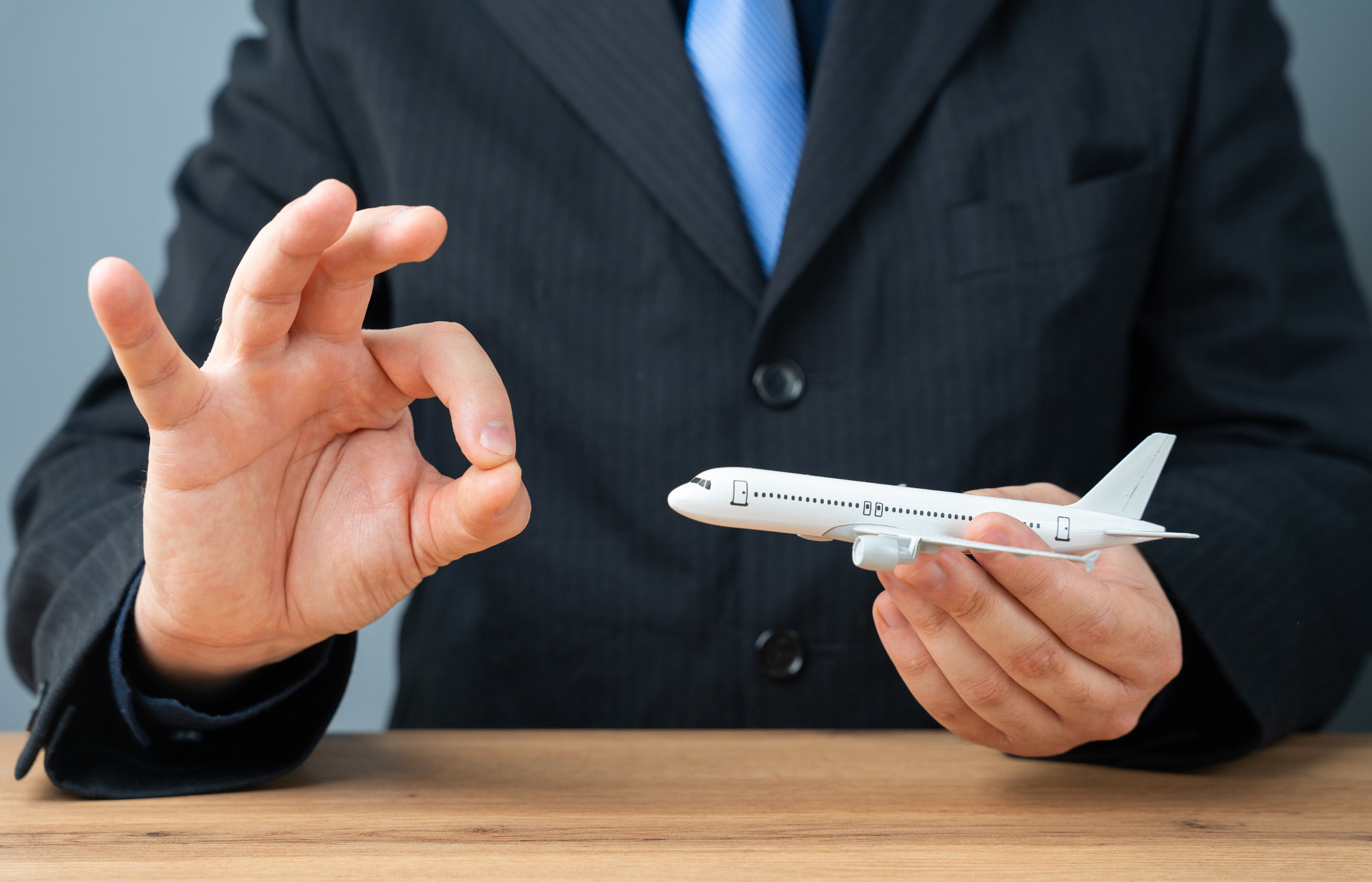 A man holds an airplane in his hands and shows the ok sign. Positive travel experiences. Flight safe