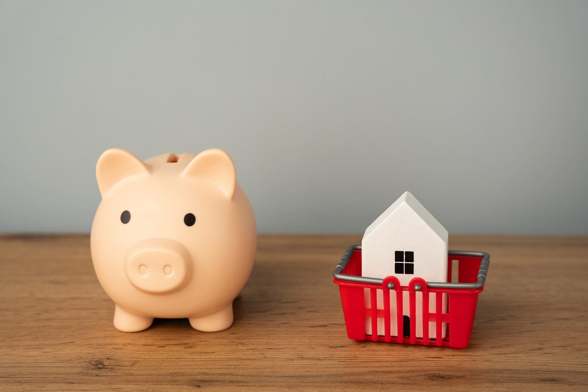 Piggy bank with house in shopping cart. Concept of buying, selling or renting a home. Mortgage, loan