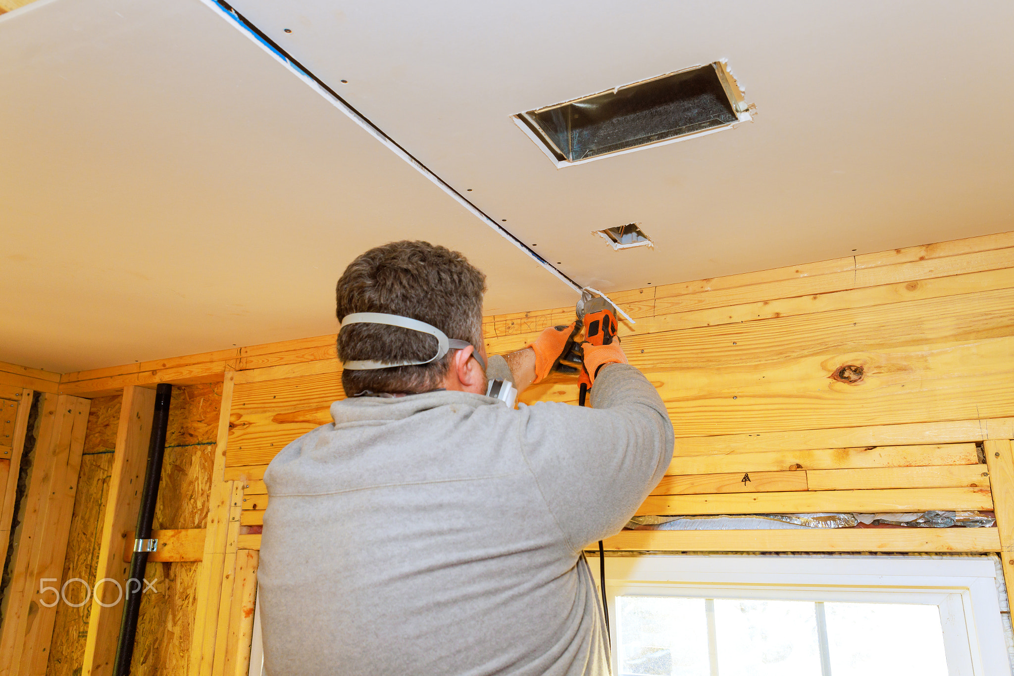 Man installing drywall in a home renovation project on a sunny