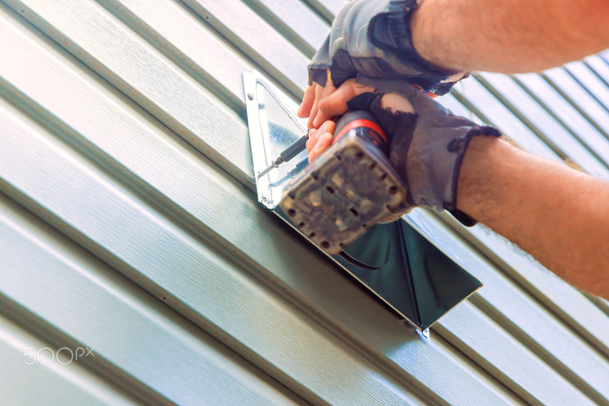 Hands working with a power drill to install a metal fixture on a