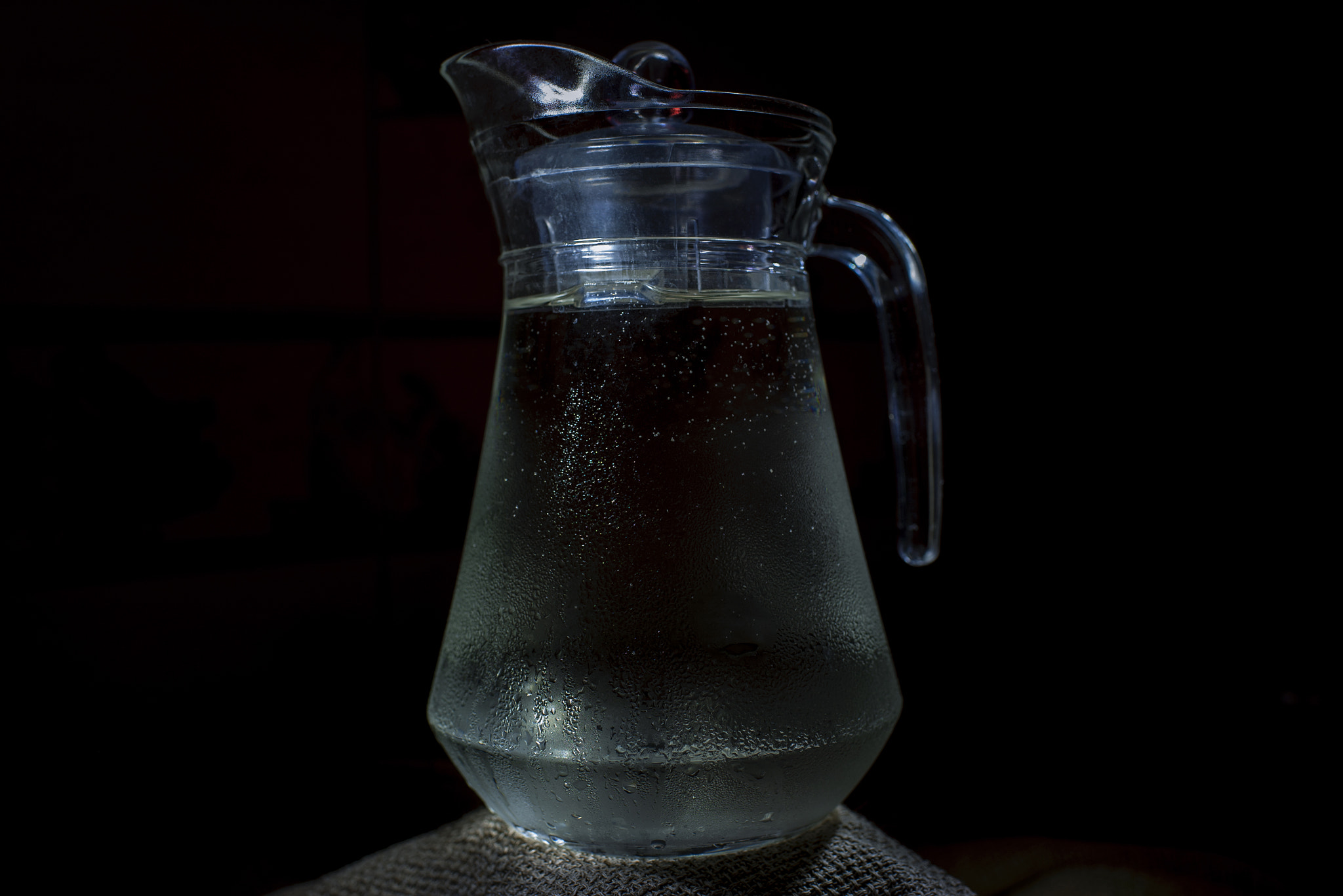 Glass jug of water on the table. Place for text, for advertising, menus and printed materials.Dark b