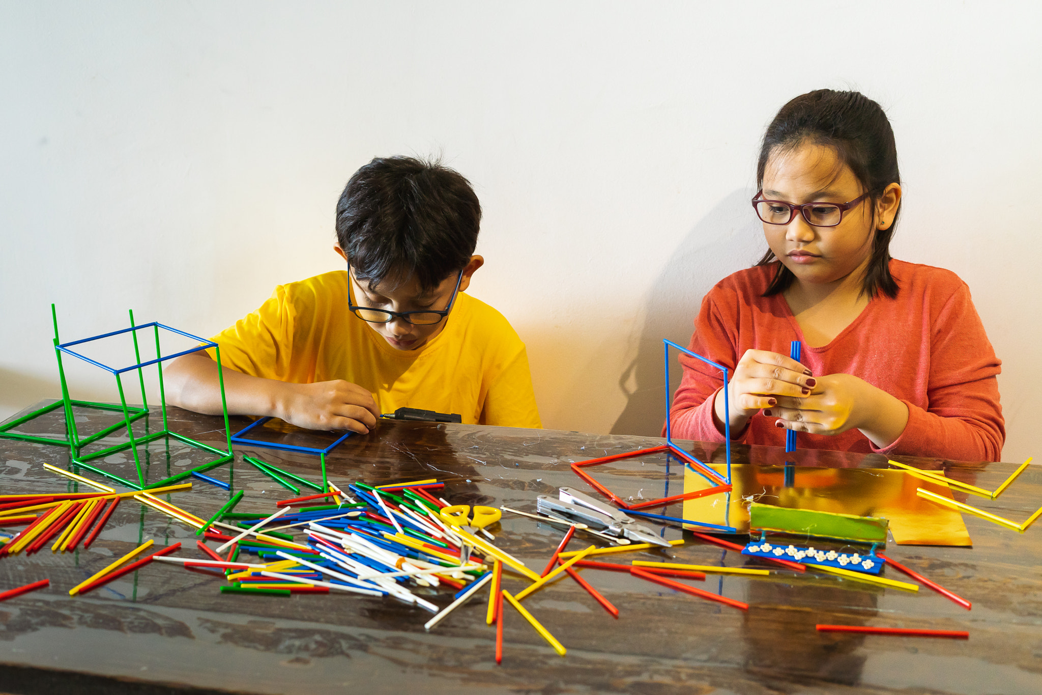 Young children are constructing colorful plastic sticks with glue gun. fun with building geometric f