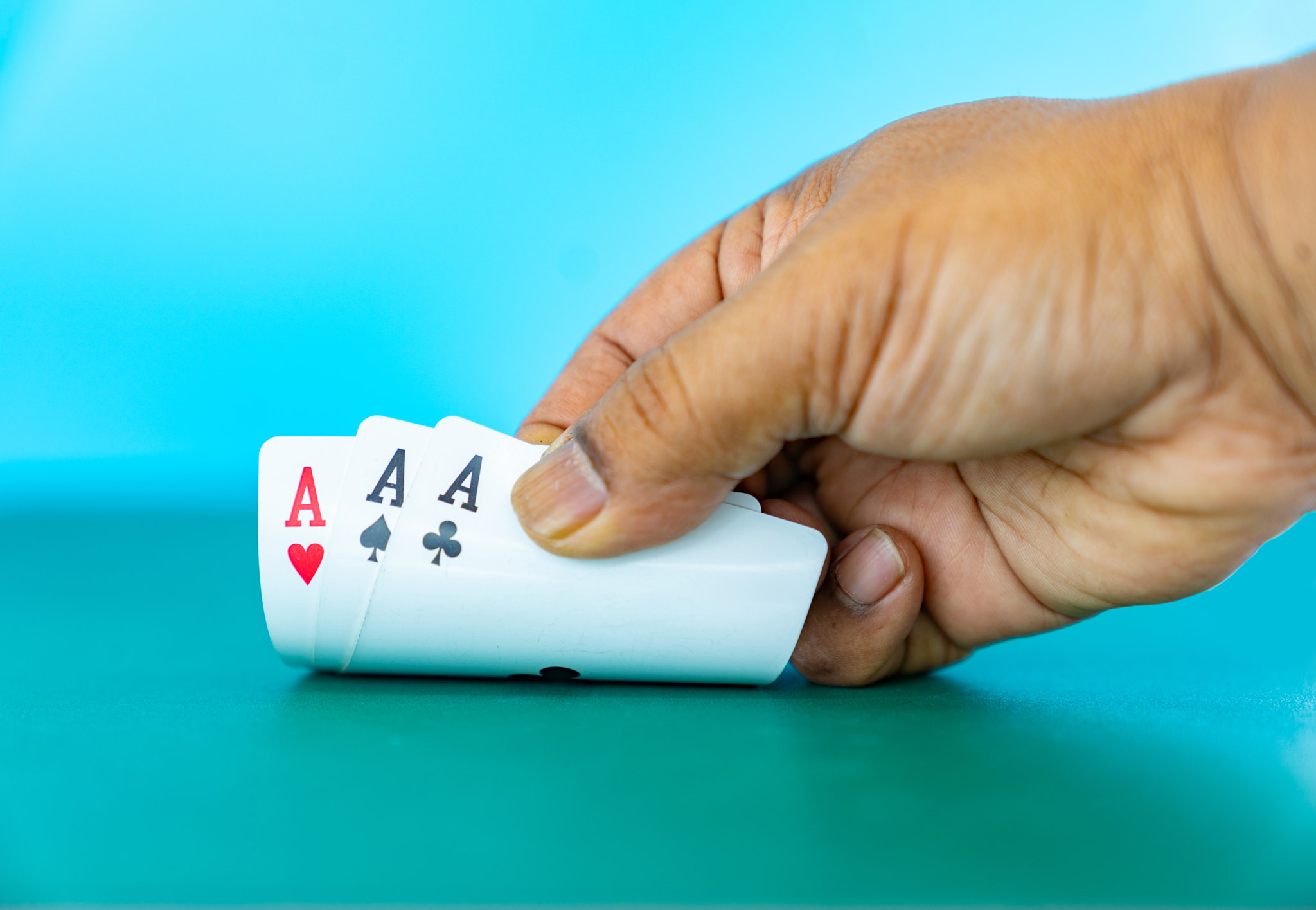 Close up hand flip playing card on aqua background.