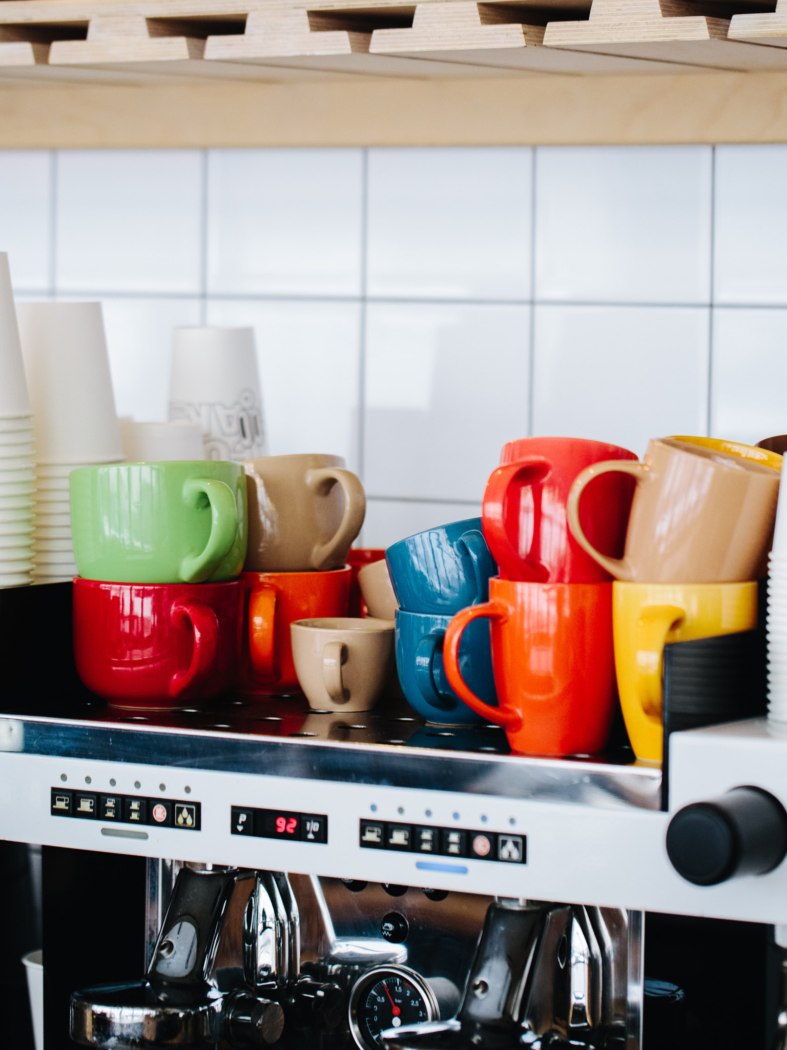 Colorful Assorted Mugs Stacked on Coffee Machine in a Cozy Kitchen Setting