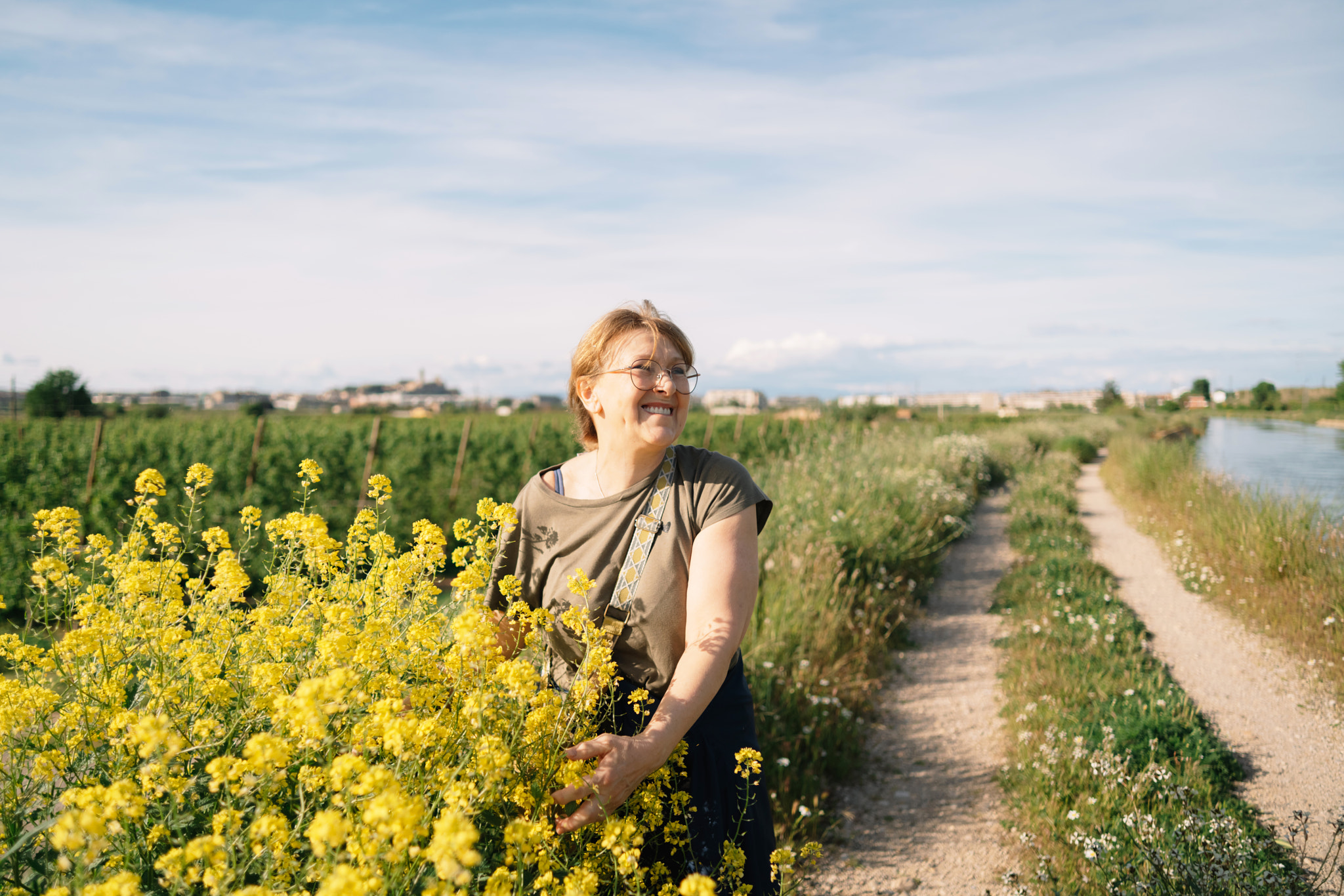 Smiling woman standing amidst plants on field
