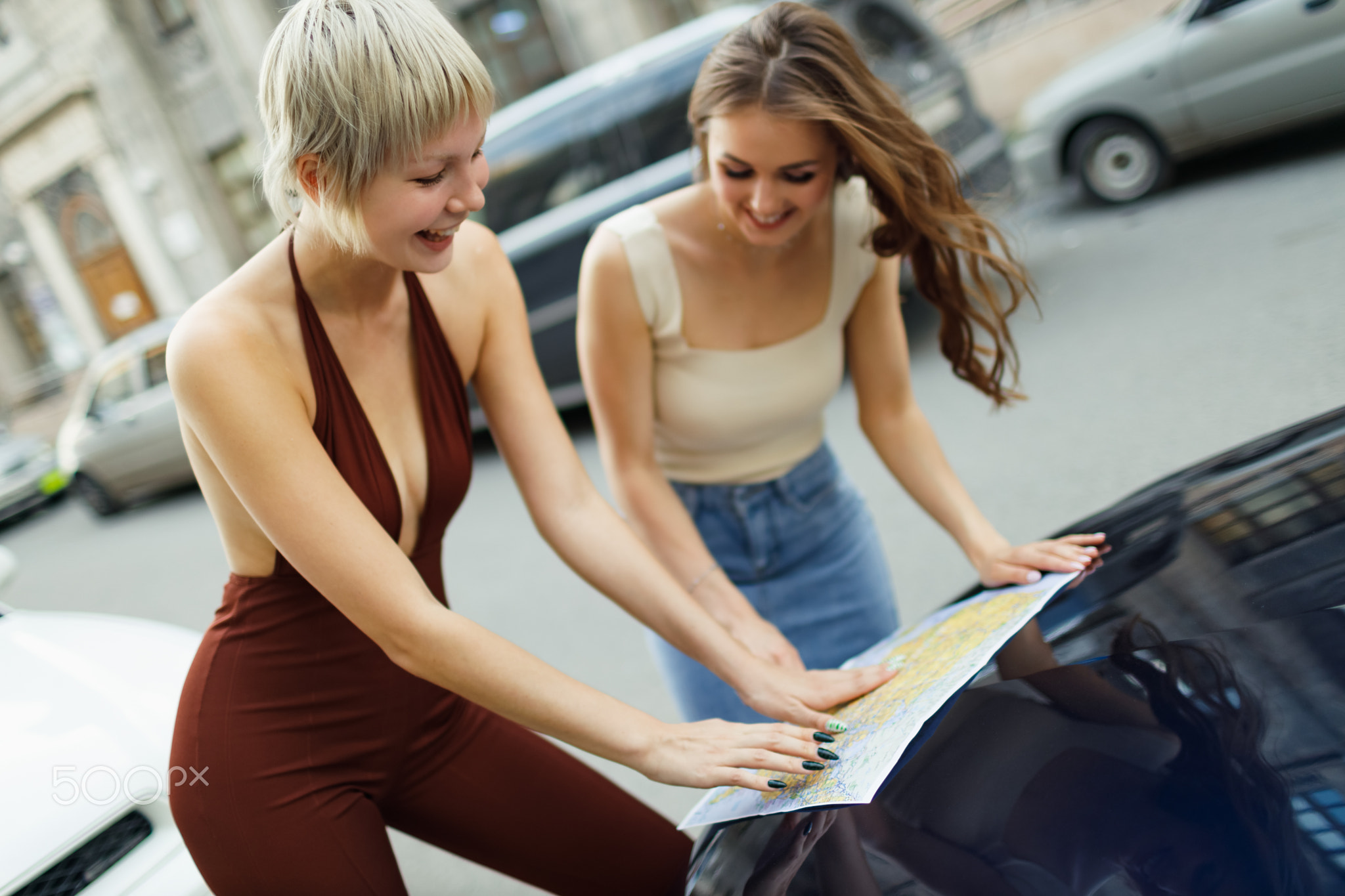 Happy young two women tourist travelers with paper map at rental car