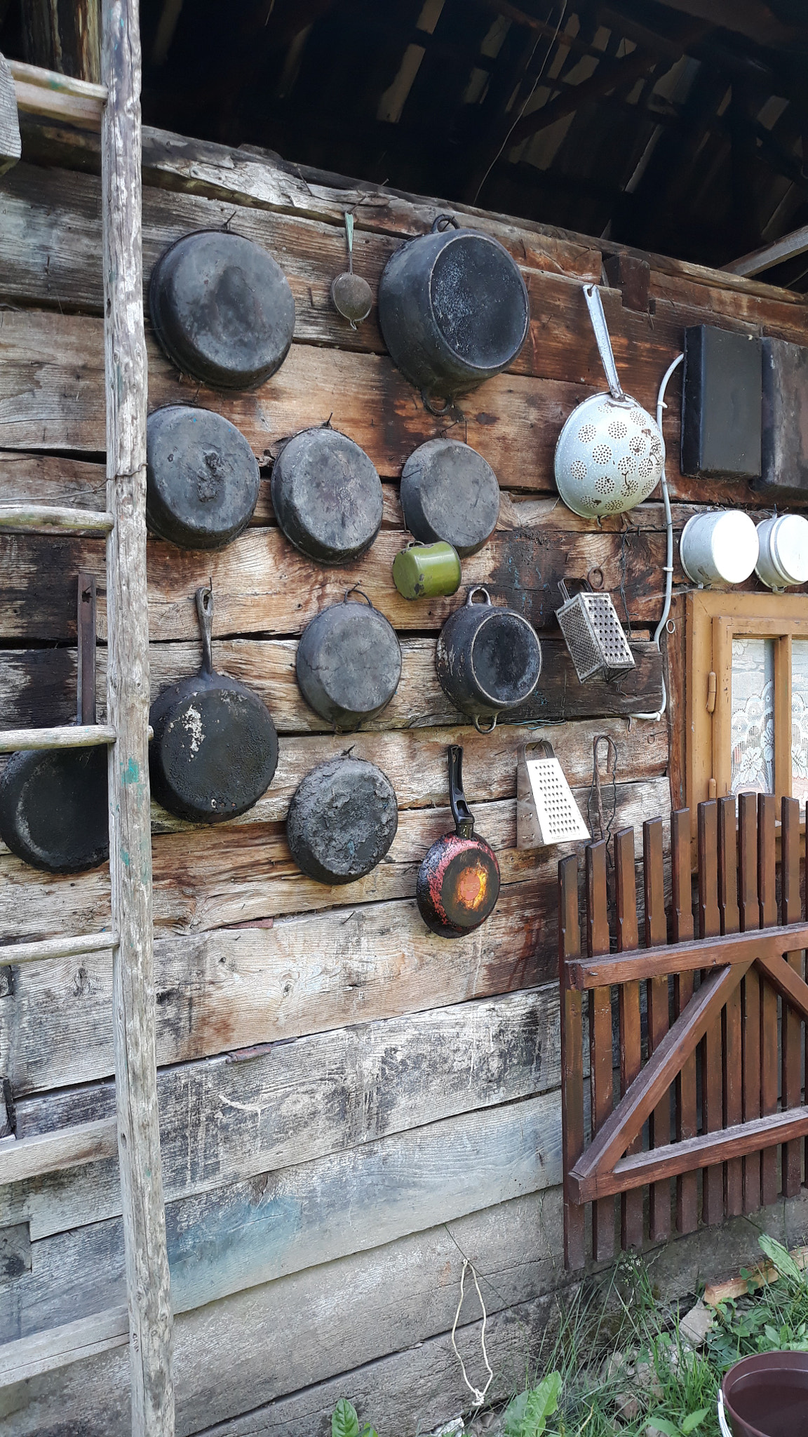 Old kitchen utensils displayed on rustic wooden wall cottage outdoors