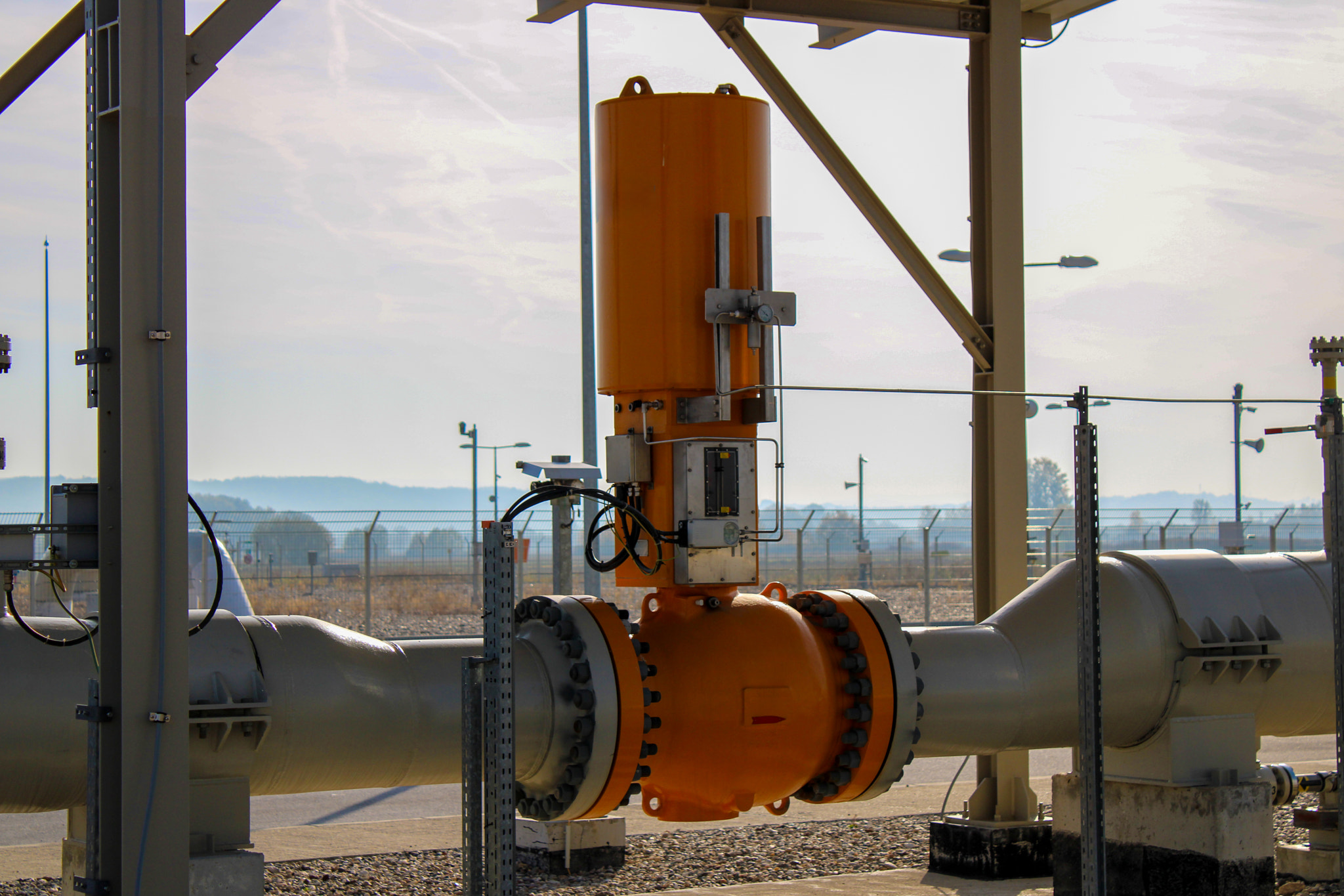 A large industrial valve system is mounted on a heavy-duty gas pipeline at an outdoor facility