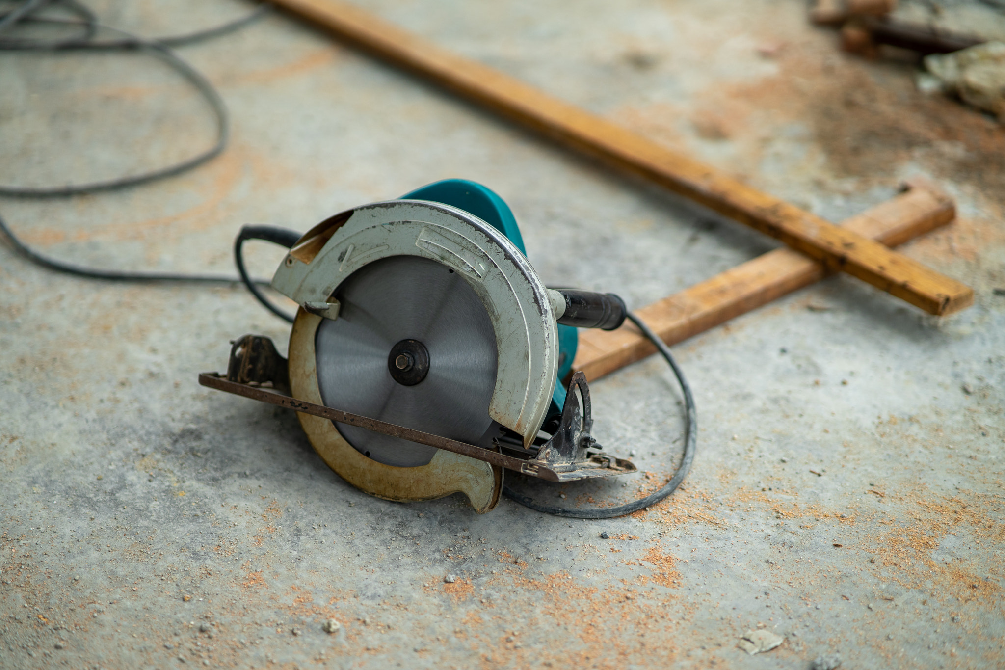 portable circular saw tool with long wires to cut wood in a construction site.