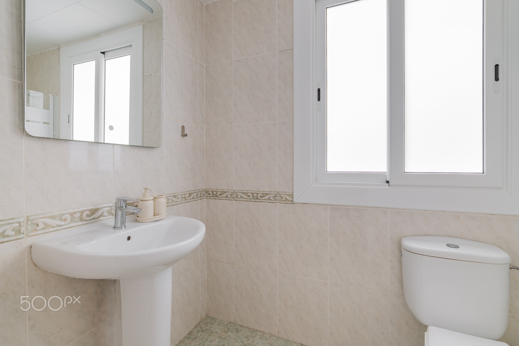 Bright bathroom corner with pedestal sink white ceramic tiles and wide frosted window