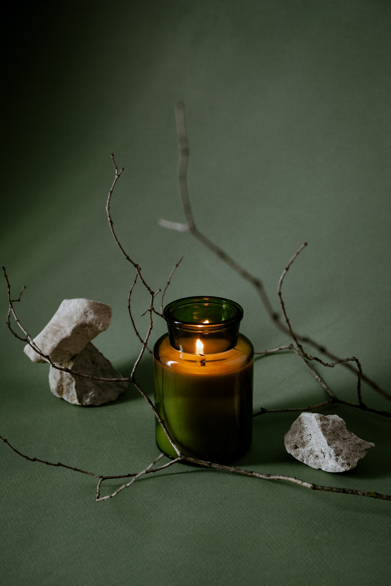 Minimalist artistic still life composition of a candle with natural elements stones and tree branch