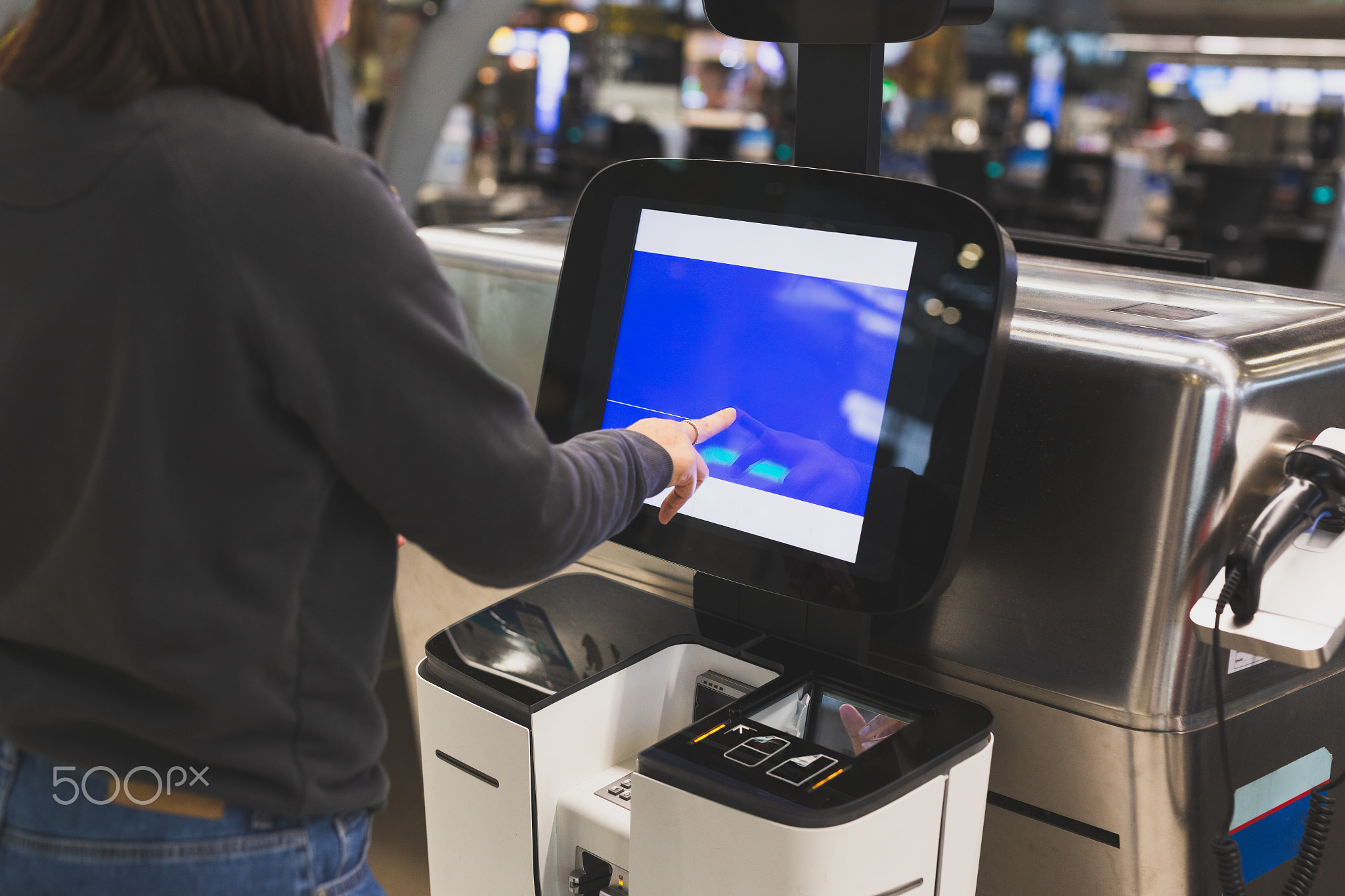 Woman using service machine for self check in at airport.