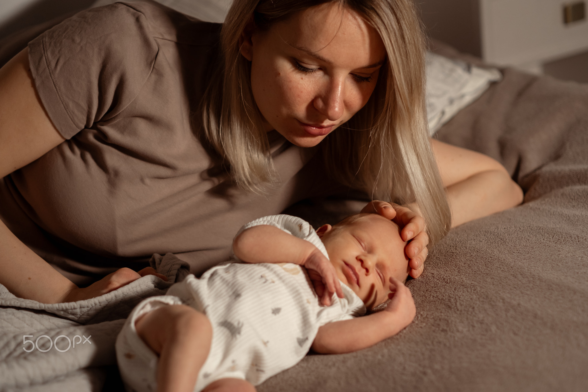 Mother gently caring for her sleeping baby at home during the evening