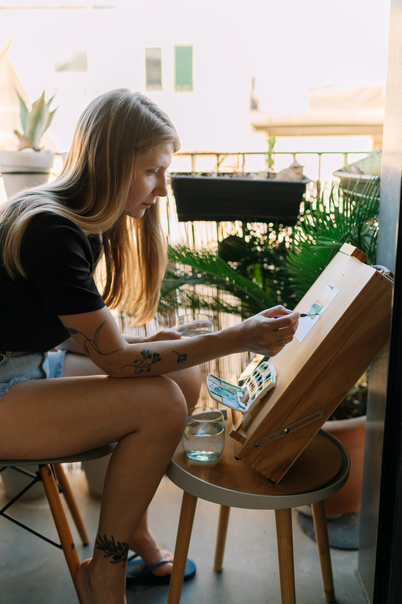 Side view of woman painting on canvas while sitting at the balcony