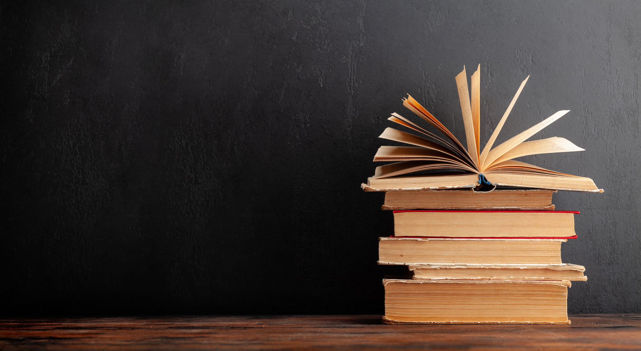 Old books on wooden table and blackboard