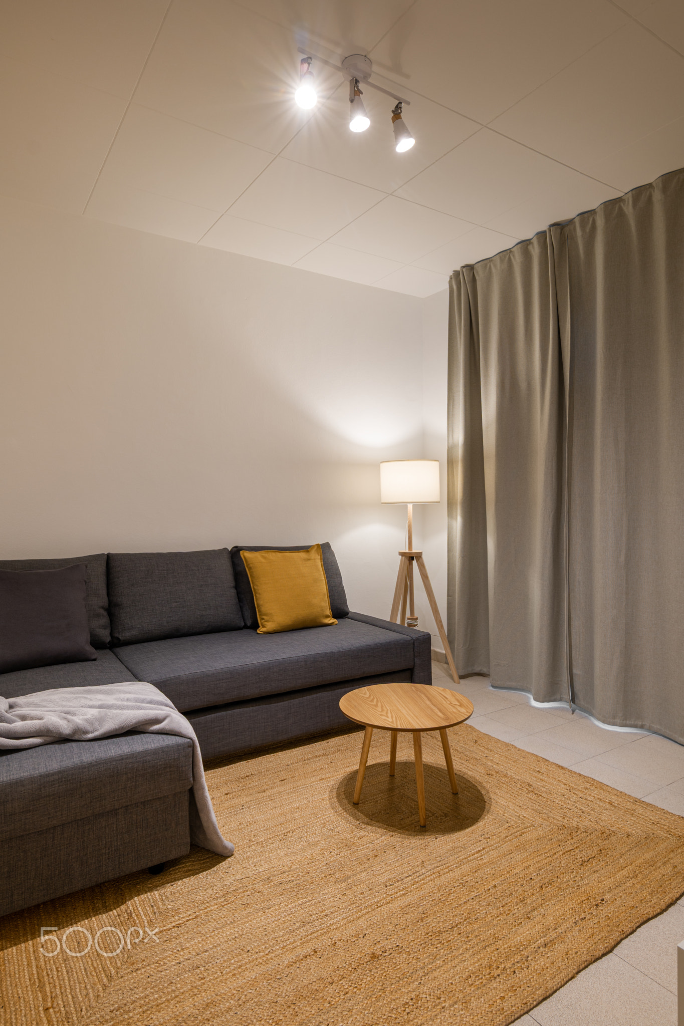 Cozy living room with gray sectional sofa, wooden coffee table and soft lighting creating a calm