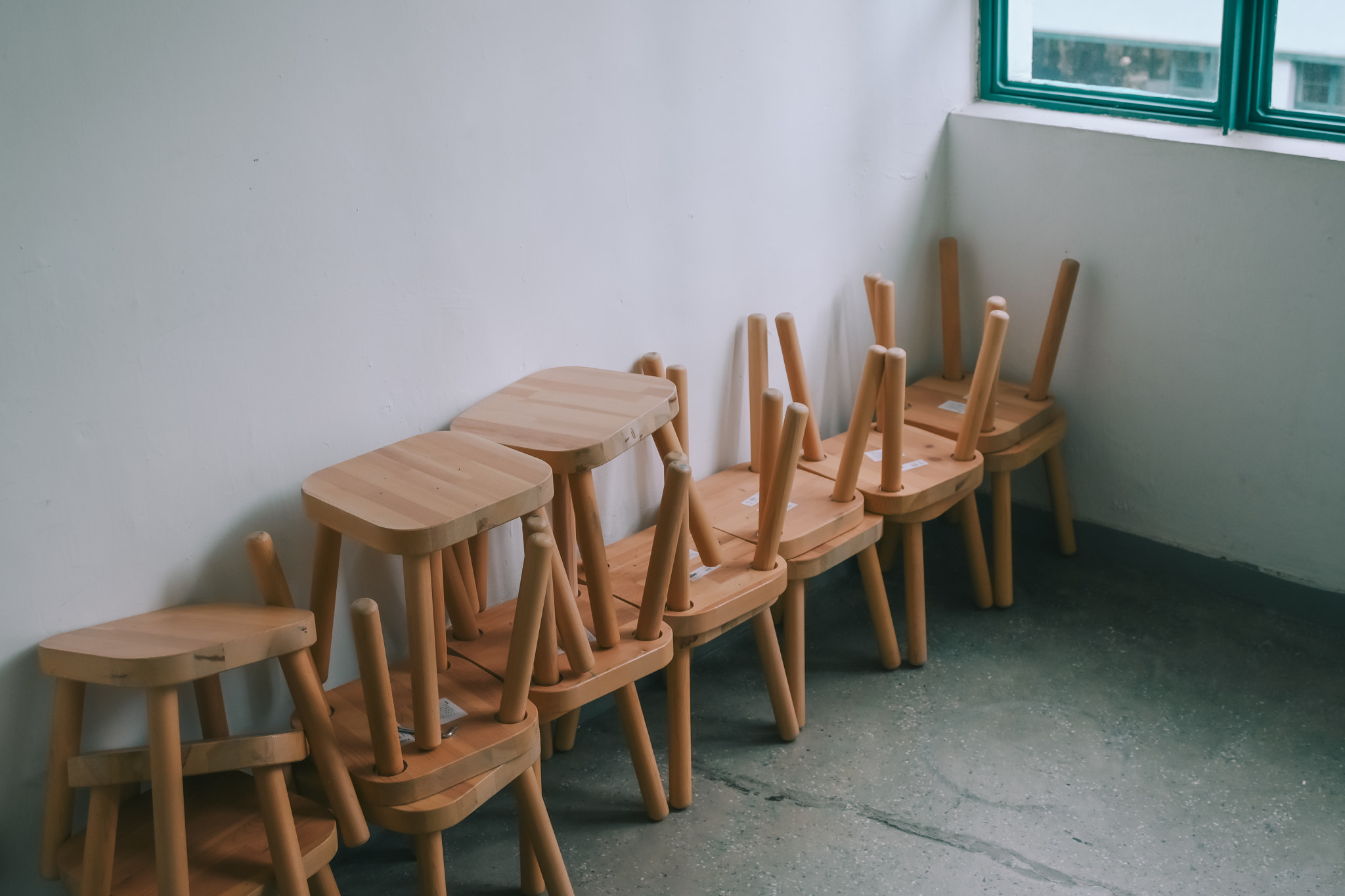 Stacked Wooden Stools Along White Wall in Minimalist Room