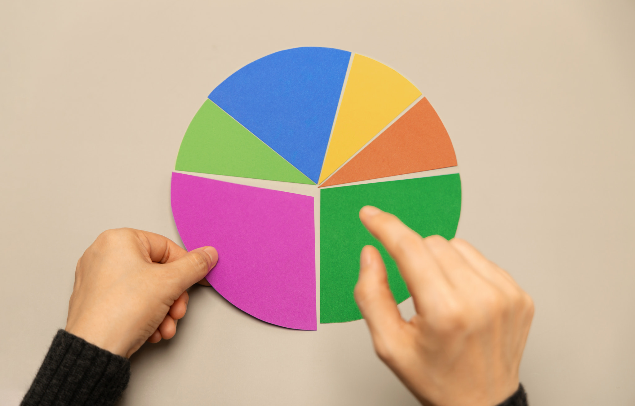 Hand selecting a segment on a colorful pie chart representing data analysis, investment portfolio al