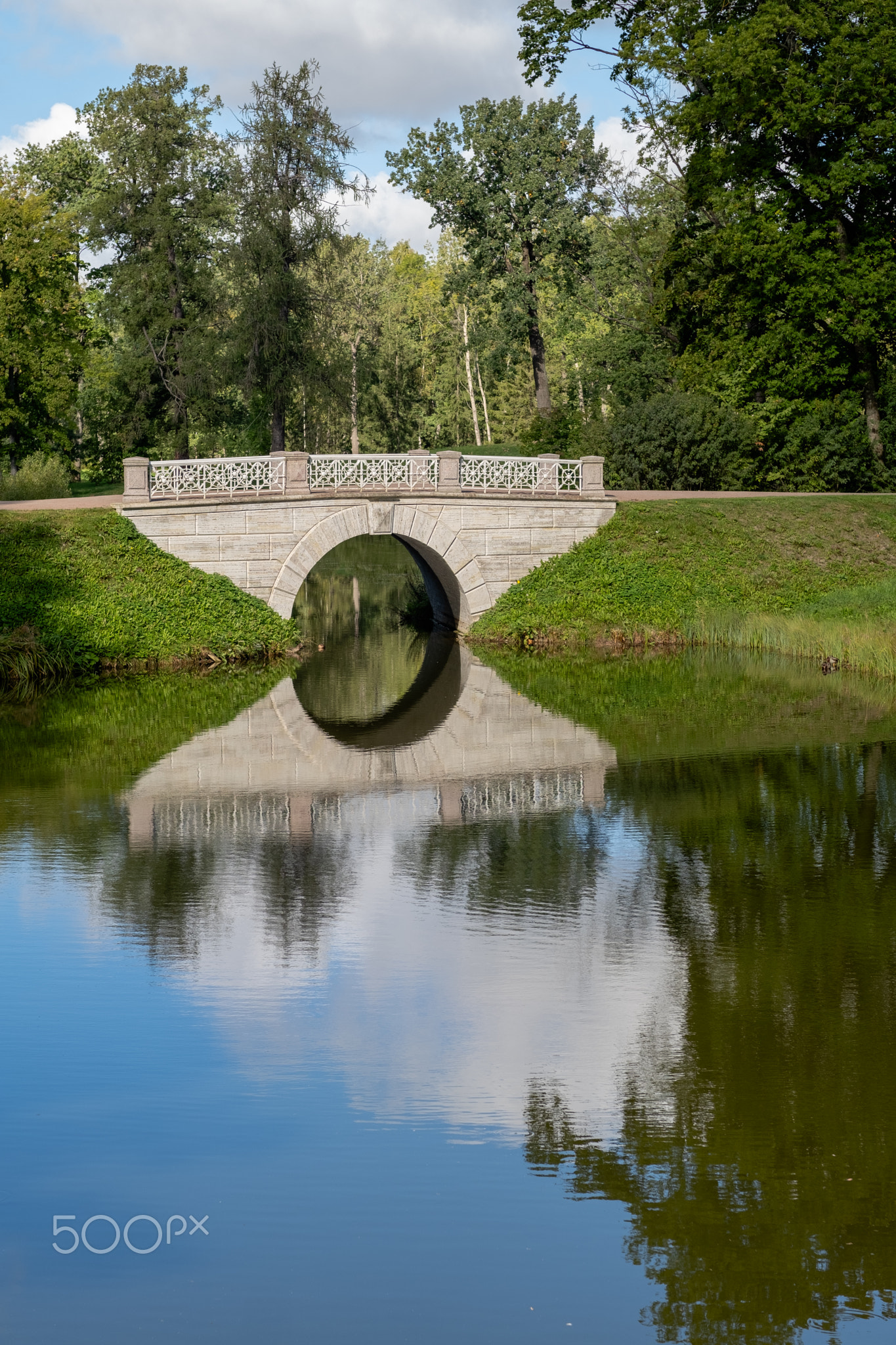 Stunning reflection of the Great Catherine Palace bridge in a serene nature setting under a clear