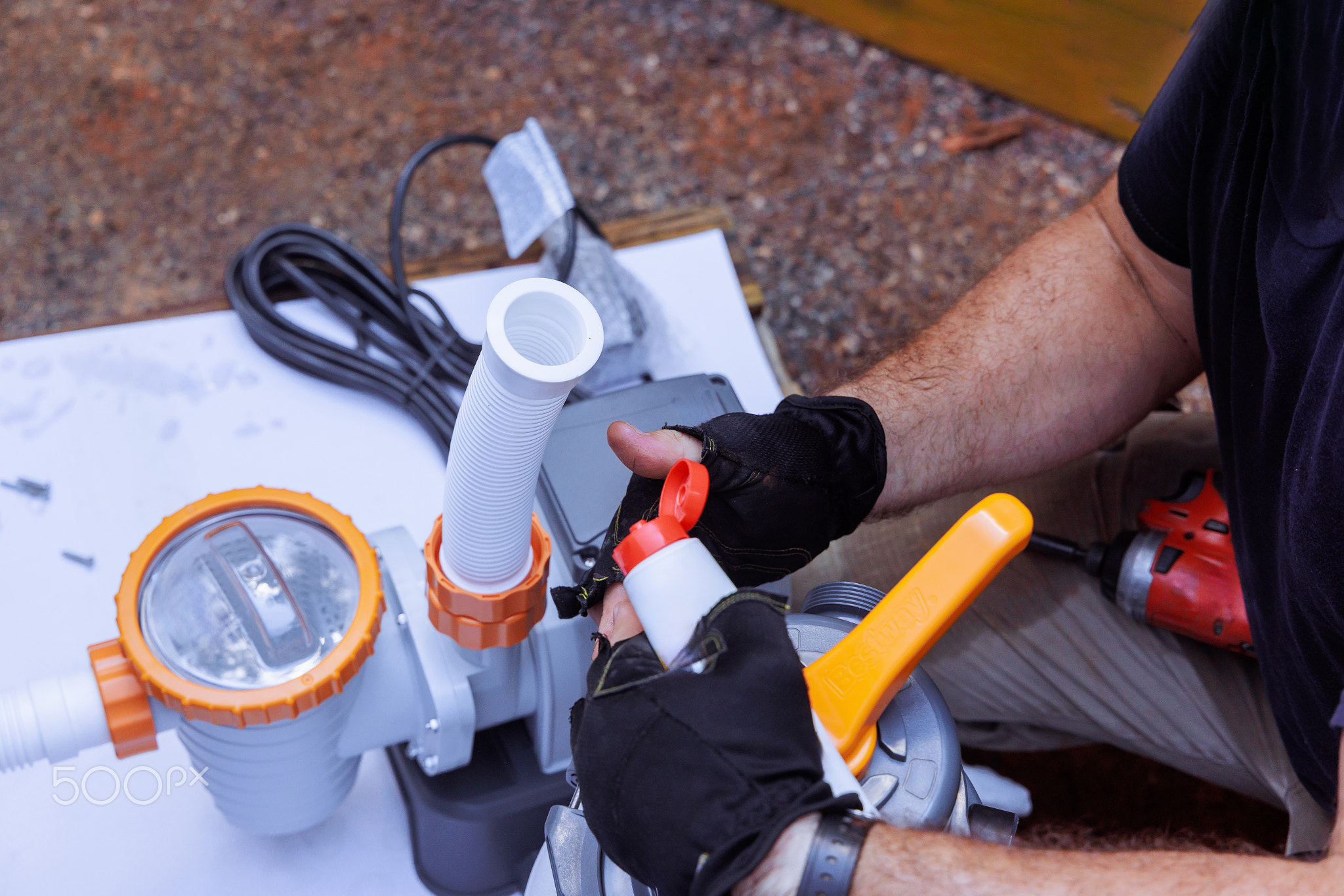Man repairing pool pump on work table outdoors in afternoon sunlight